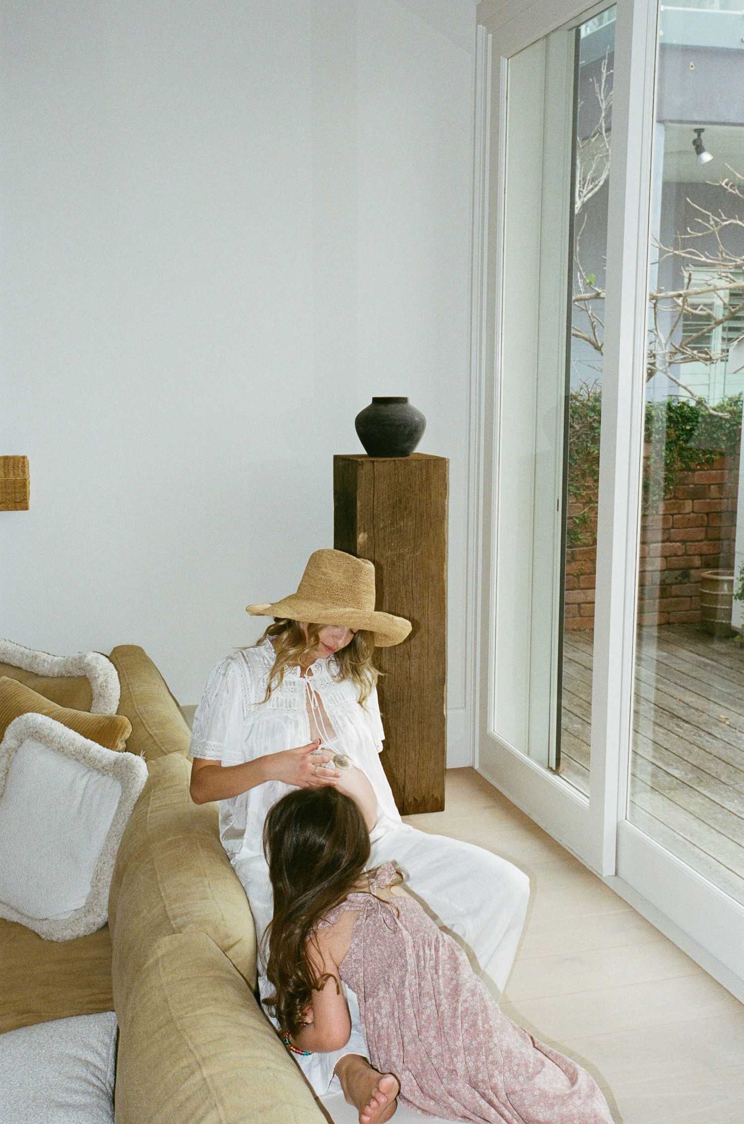 A series of four photos showing a person in a sun hat resting on a white couch by large windows.