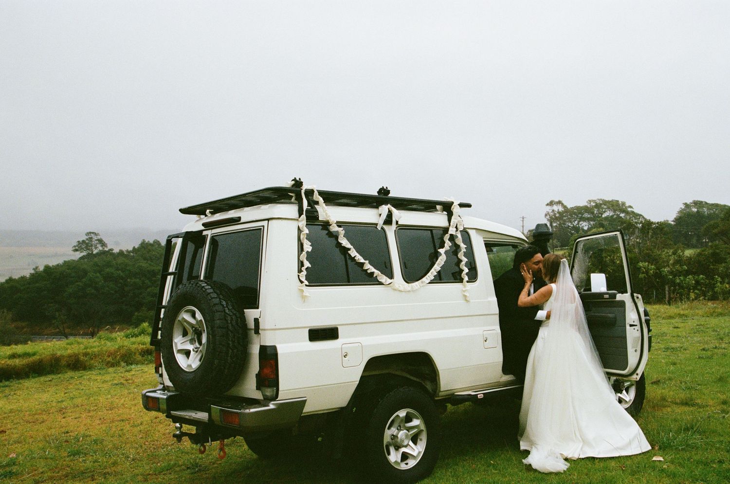 Wedding party vehicles and transportation lined up on a grassy field during an outdoor celebration.