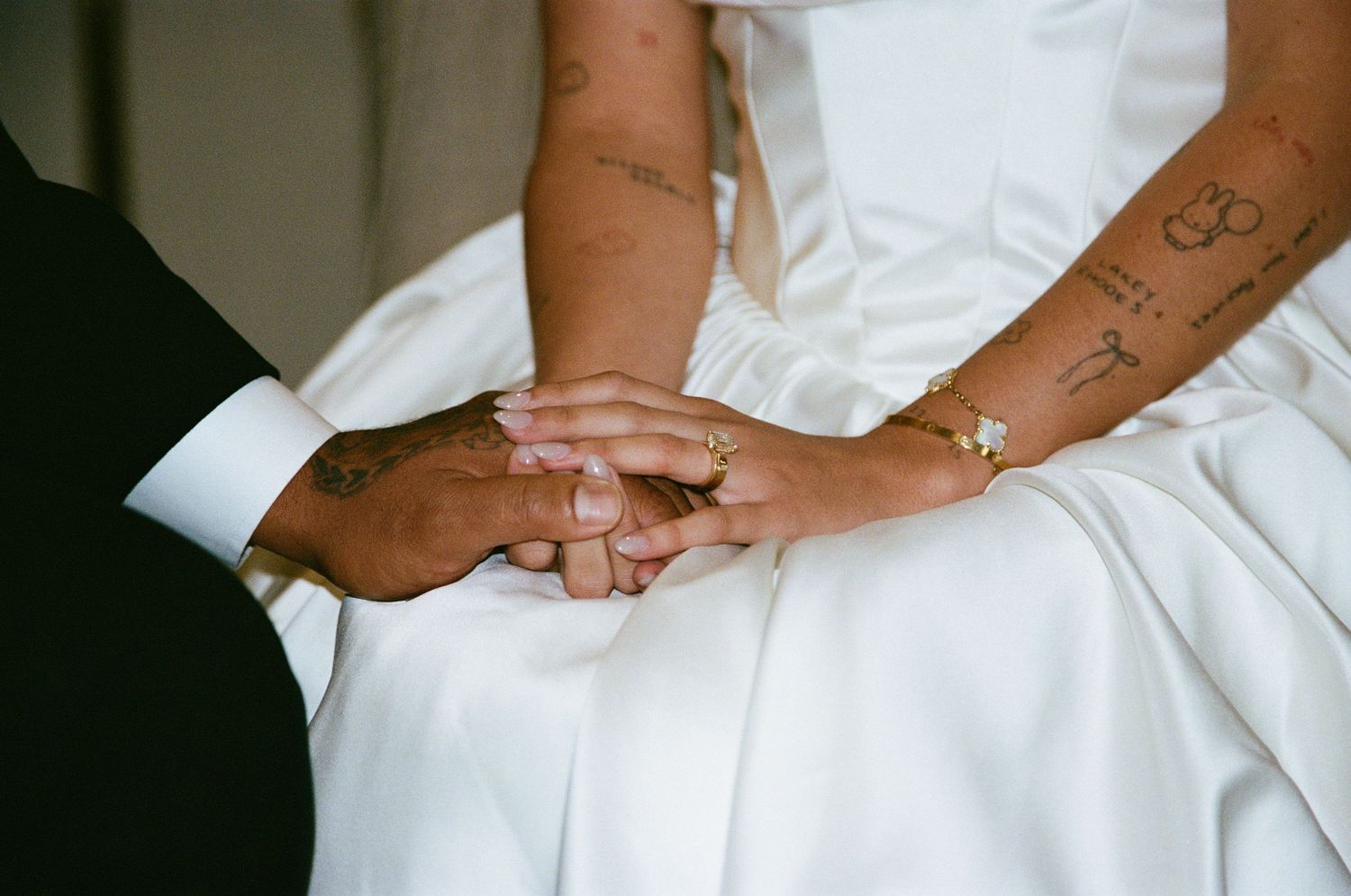 Close-up details of a white satin wedding dress showing elegant pleating and fabric texture.