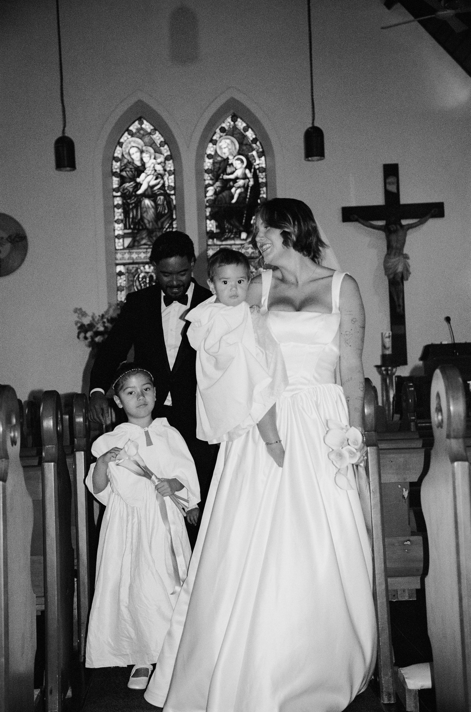 A black and white church wedding scene with gothic arches and stained glass windows.