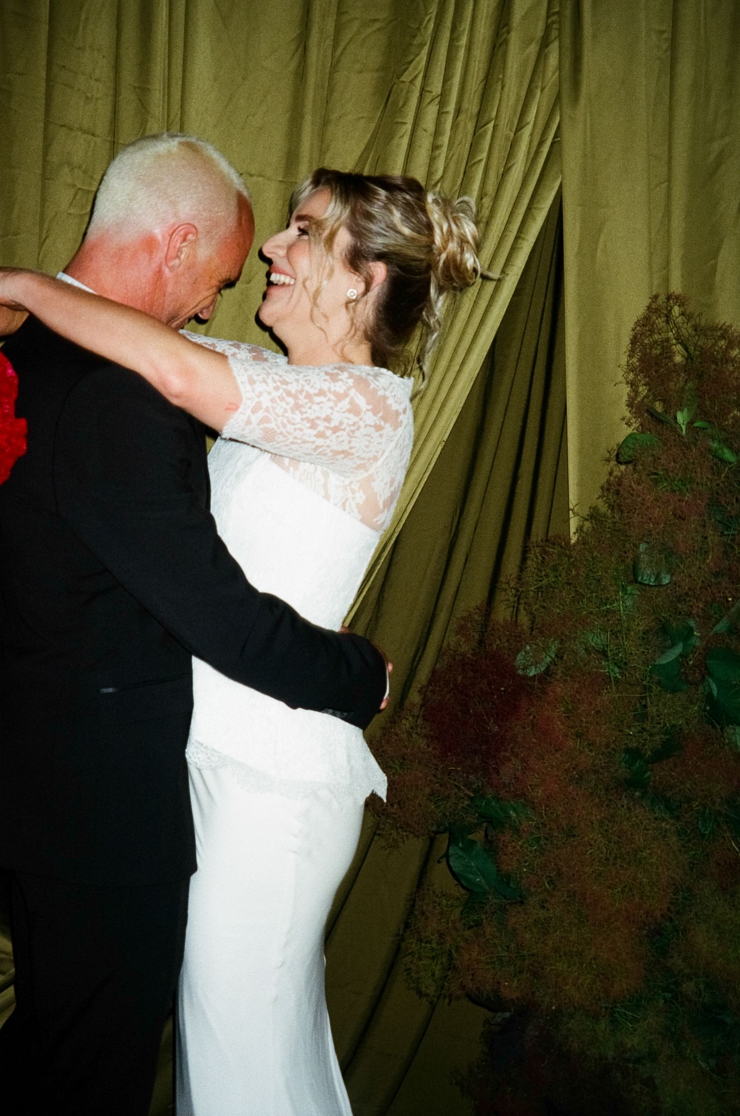 A couple shares a romantic dance moment at their wedding reception with dim lighting in the background.