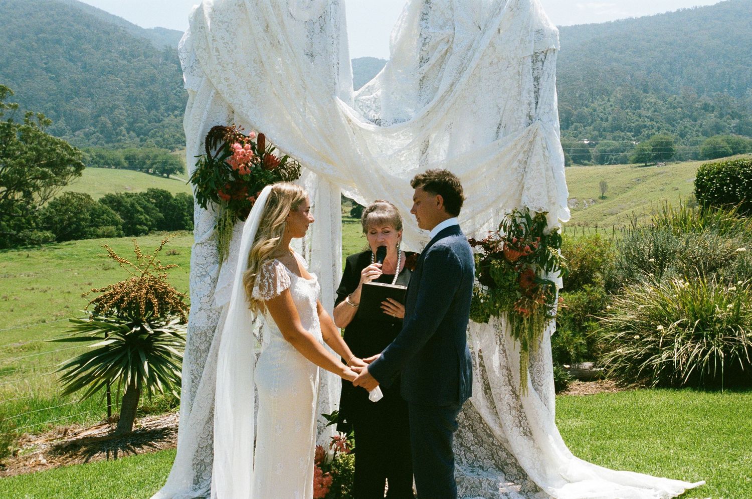 An outdoor wedding ceremony setup with white fabric draping and mountain views in the background.