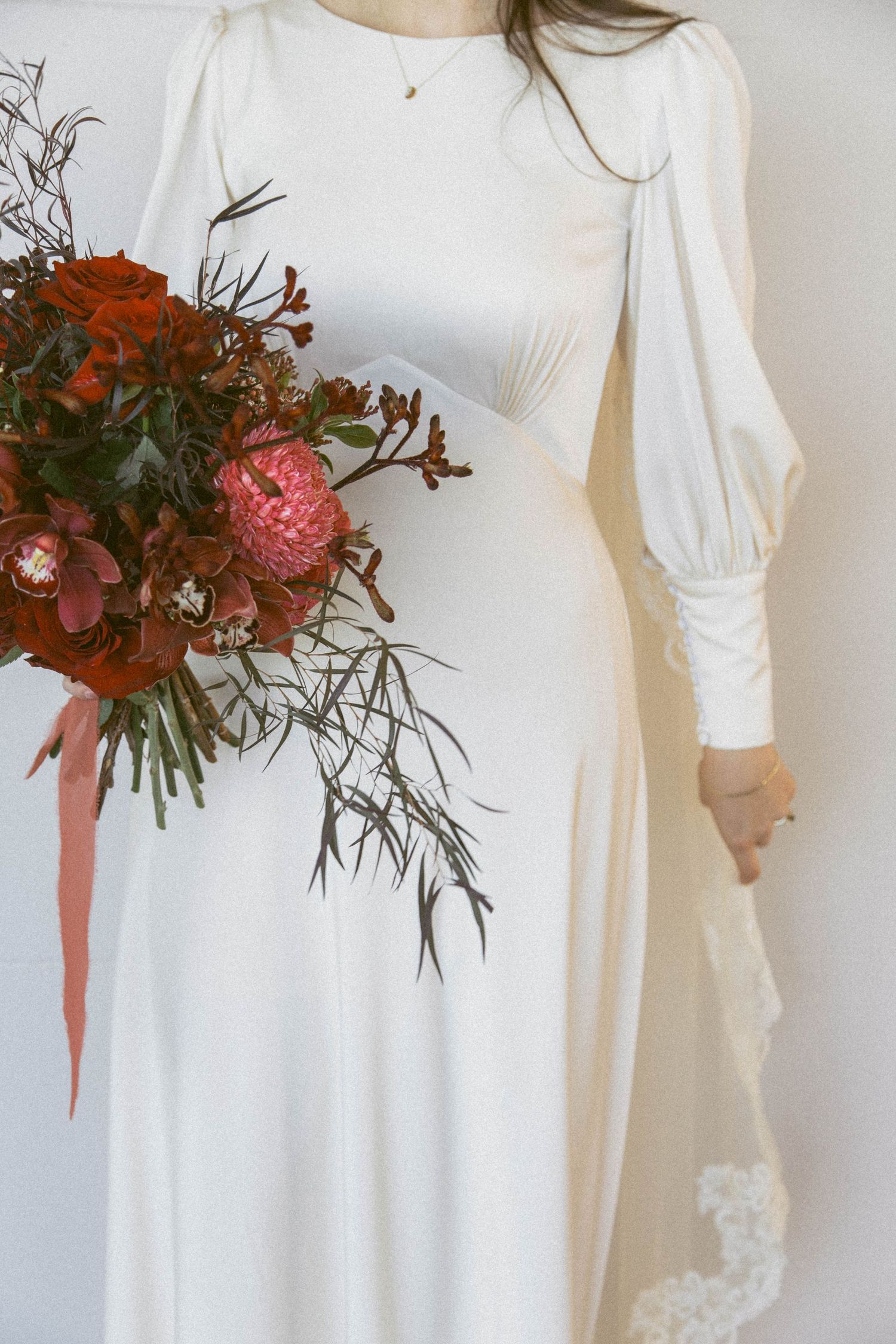 White vintage wedding dress details with delicate lace accents and flowing fabric shown with floral bouquet.
