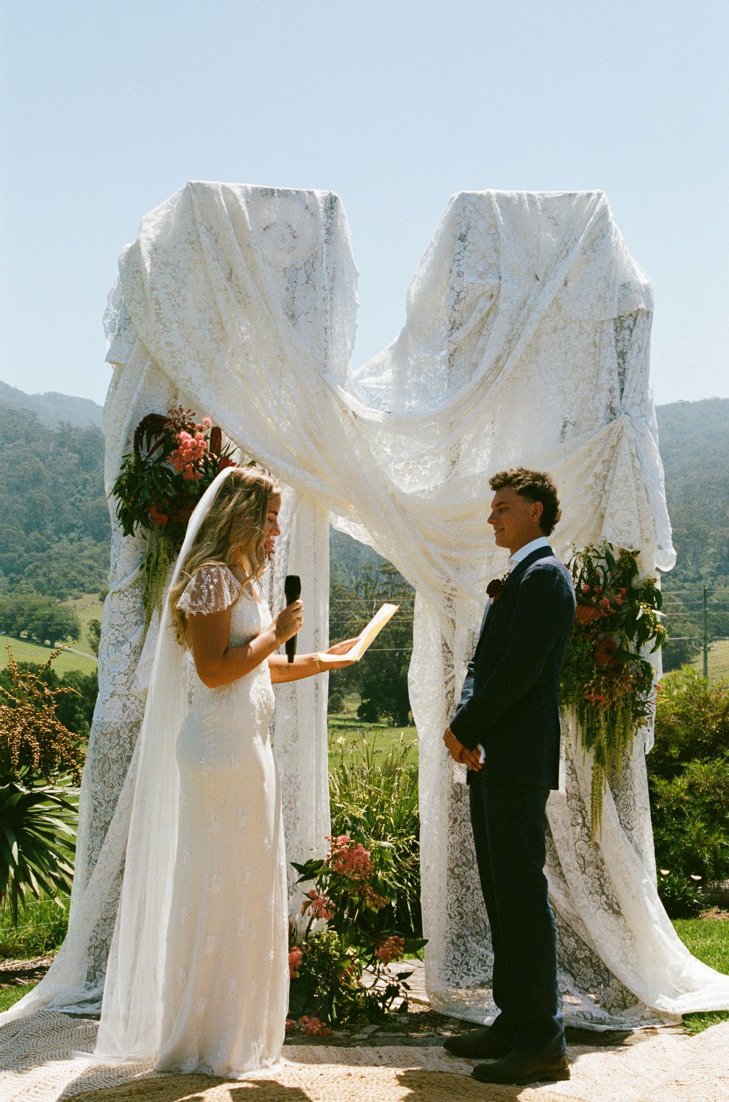 Wedding ceremony site with flowing white lace drapes against mountain backdrop.