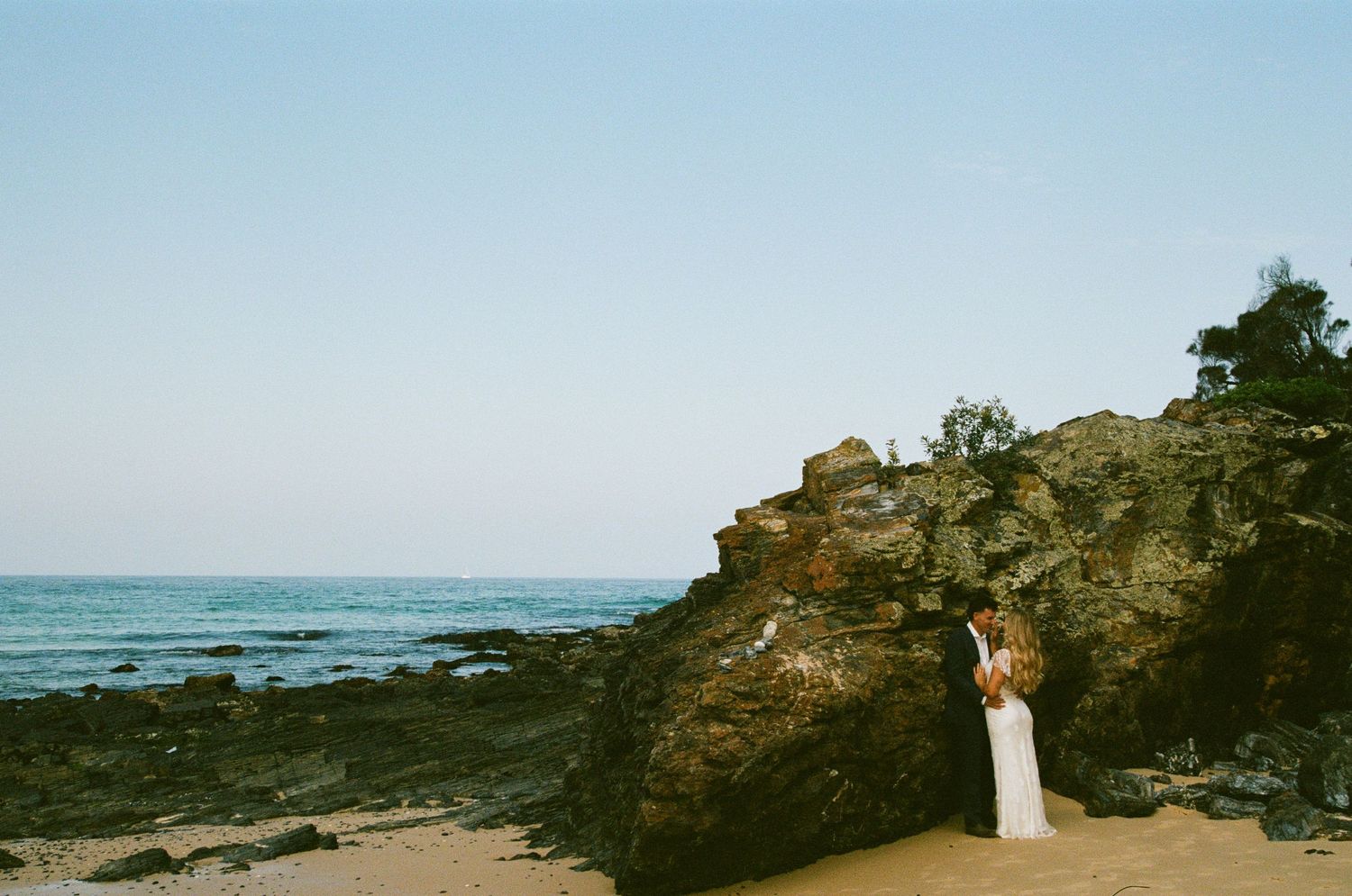 A scenic coastal landscape with rocky cliffs and ocean waves stretching along the horizon under a blue sky.