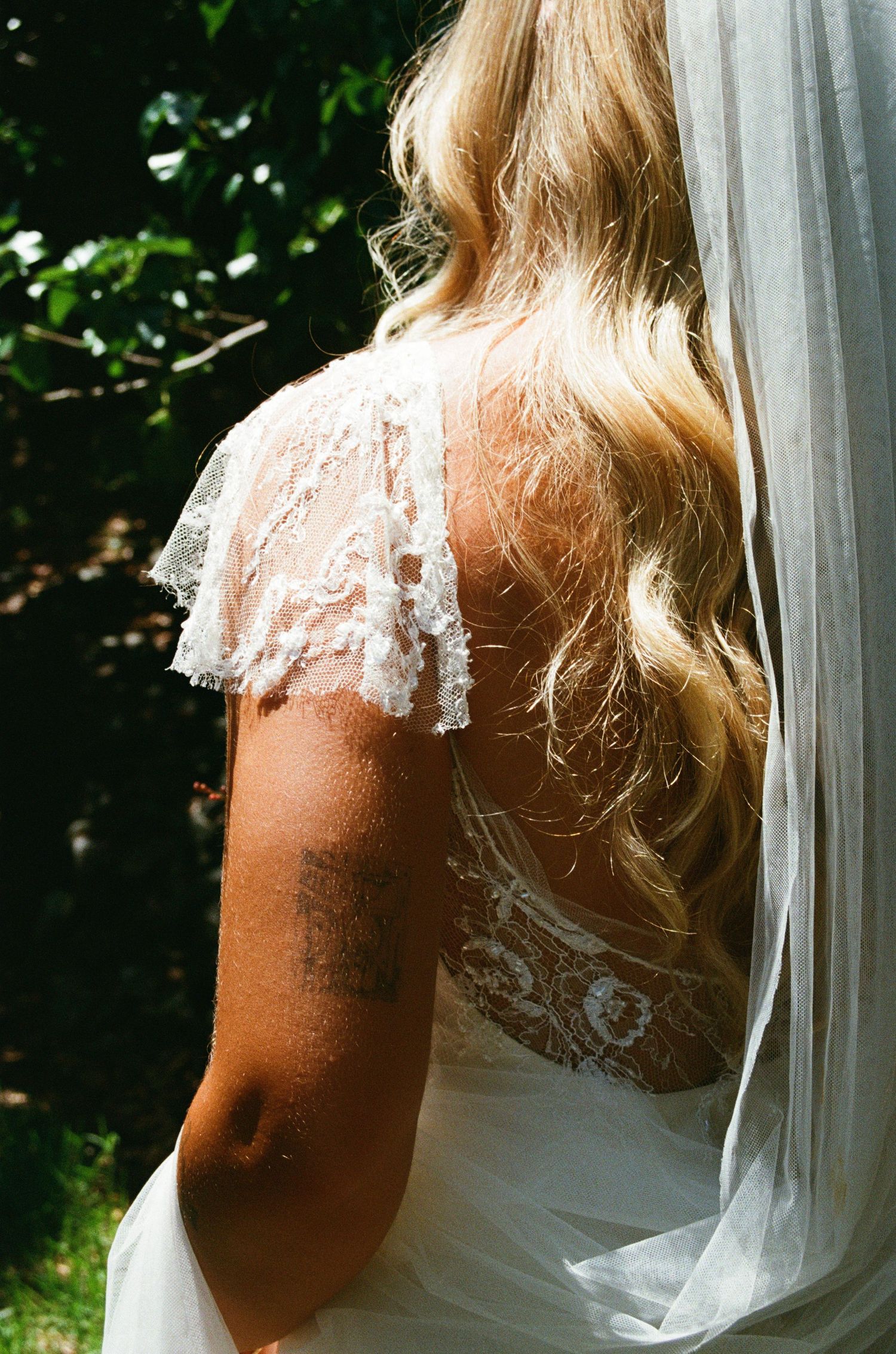 Close-up detail of delicate lace sleeve and veil on a white wedding dress.