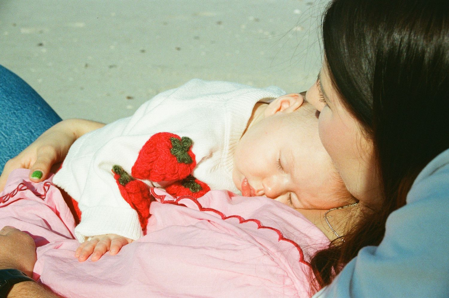 Sleeping person in white and pink clothing holds red plushy toy while reclining on blue surface.