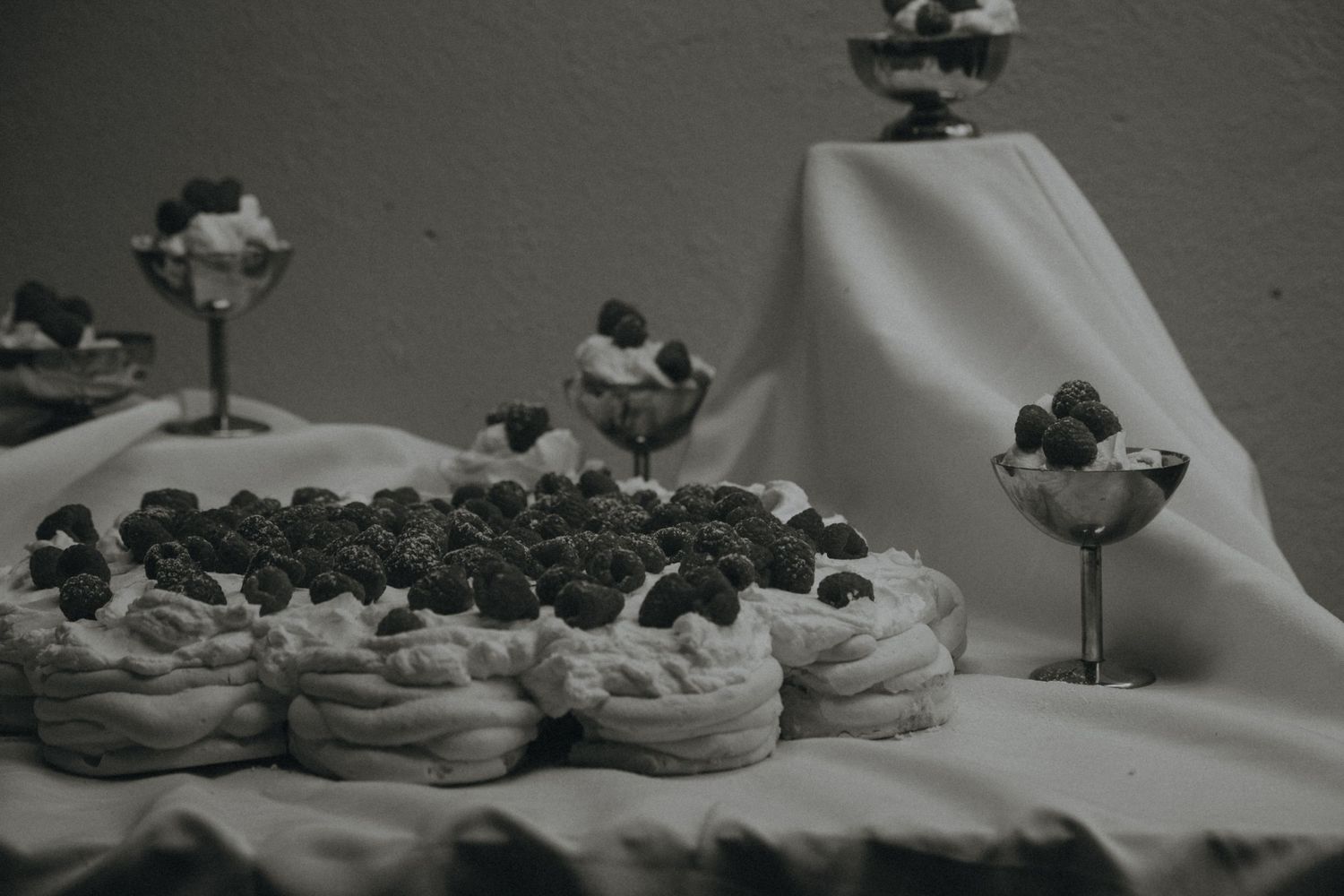 Wedding dessert table displaying an assortment of miniature treats and sweets arranged on white linens.