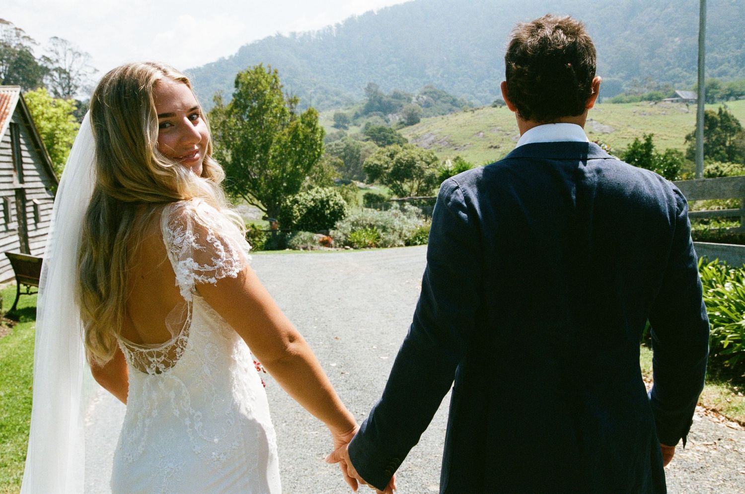 A bride and groom share a romantic moment together in a scenic outdoor setting with mountains in the background.