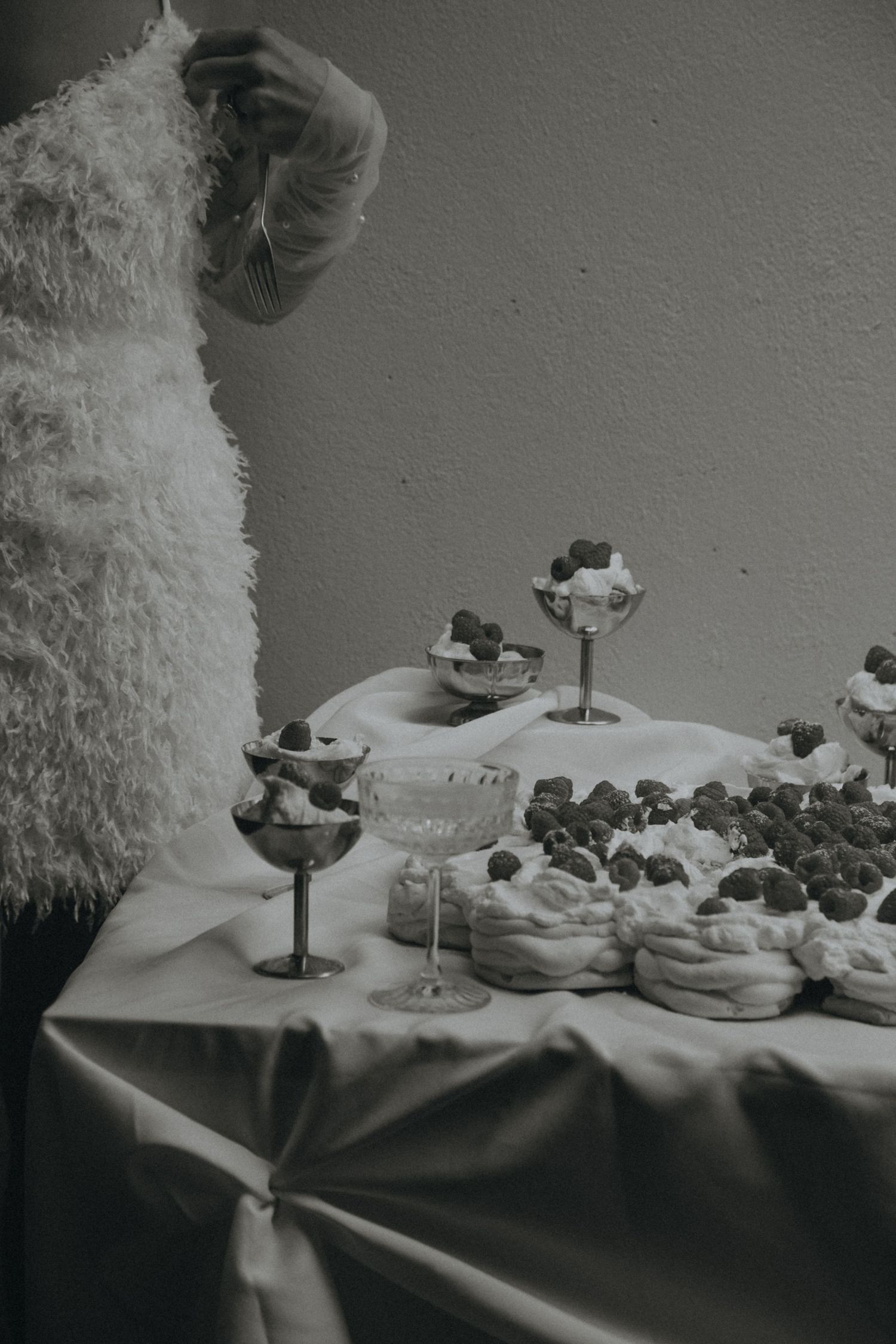 Black and white still life of cocktail glasses and appetizers arranged on a table with dramatic lighting.