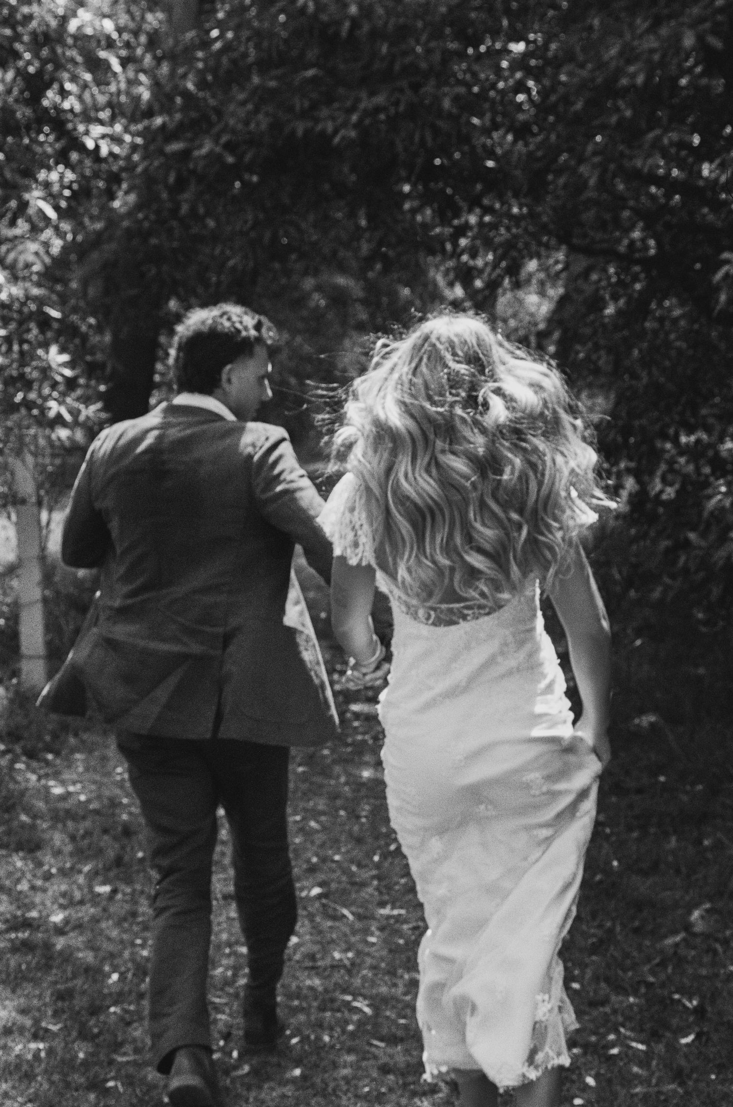 Black and white photo of people running through a garden pathway.