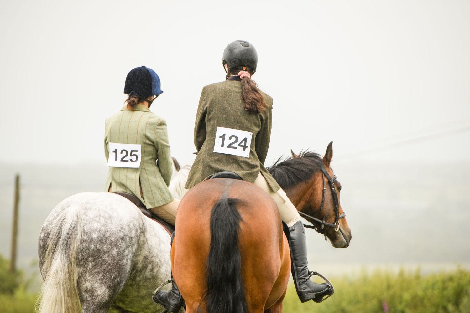 Two riders on horseback wearing competition numbers 124 and 125 during an equestrian event.