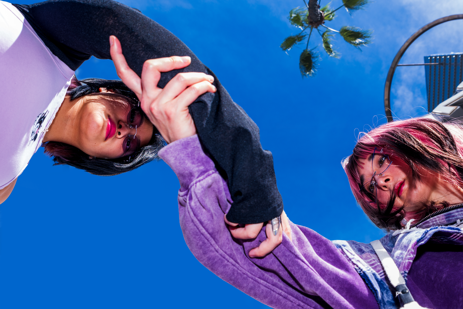 Mei and Mary from Doll Parade wearing the lens alter and Sanrio collab glasses while posing with their hands grasping each other's arms.