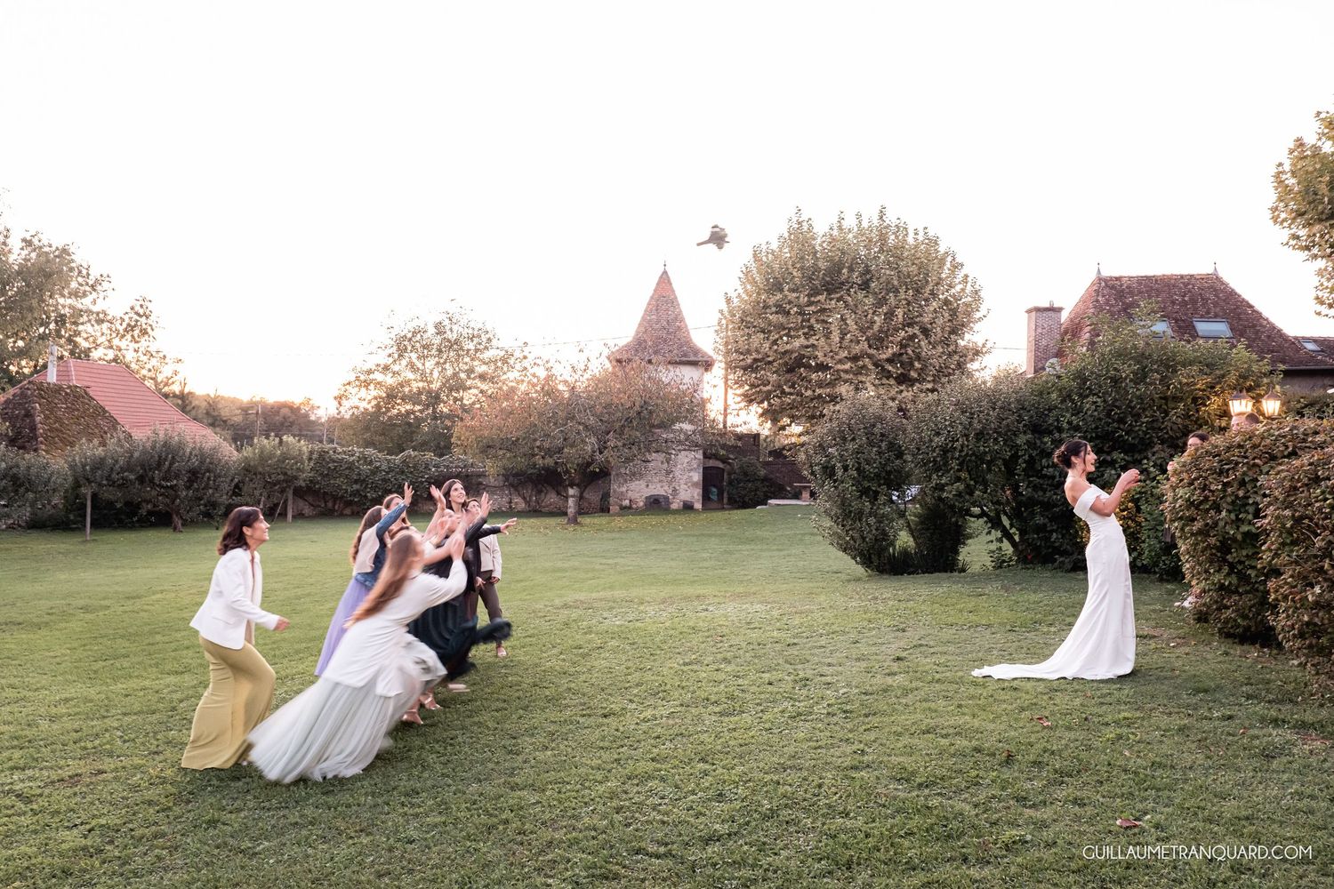 Wedding party having fun on grassy lawn during golden hour photography session.