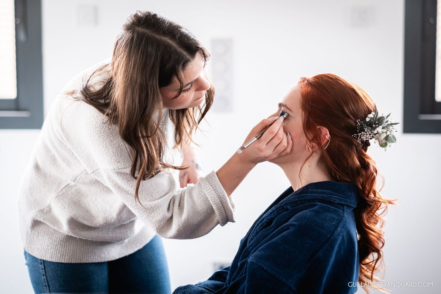 Professional makeup artist applying cosmetics in bright studio setting.