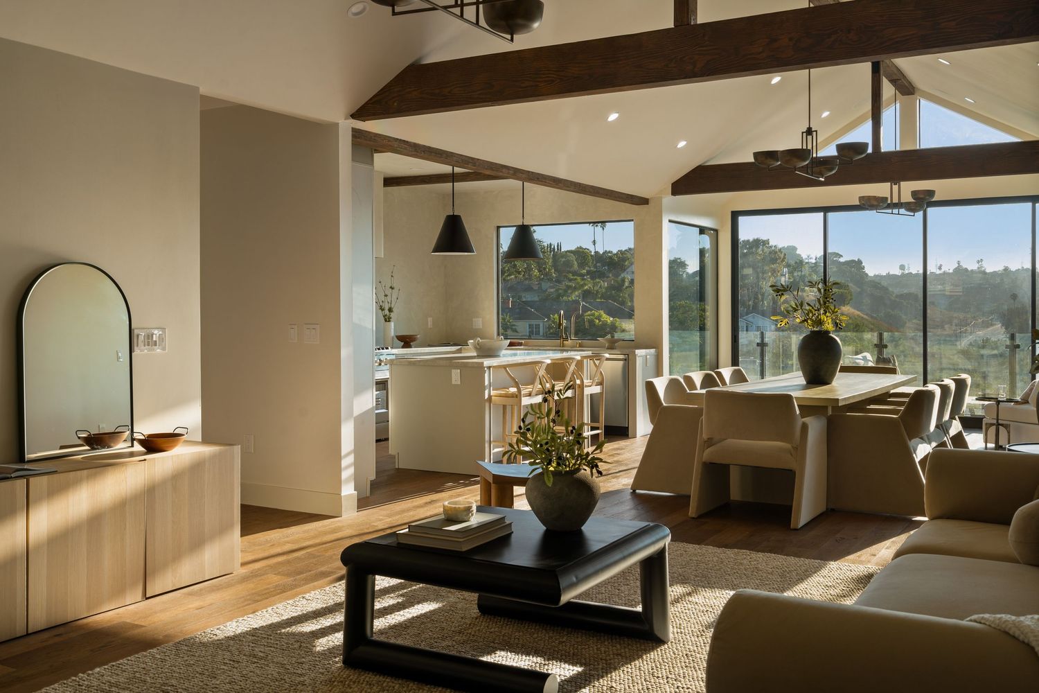Modern open concept living room with floor-to-ceiling windows overlooking mountains and natural light illuminating the space.