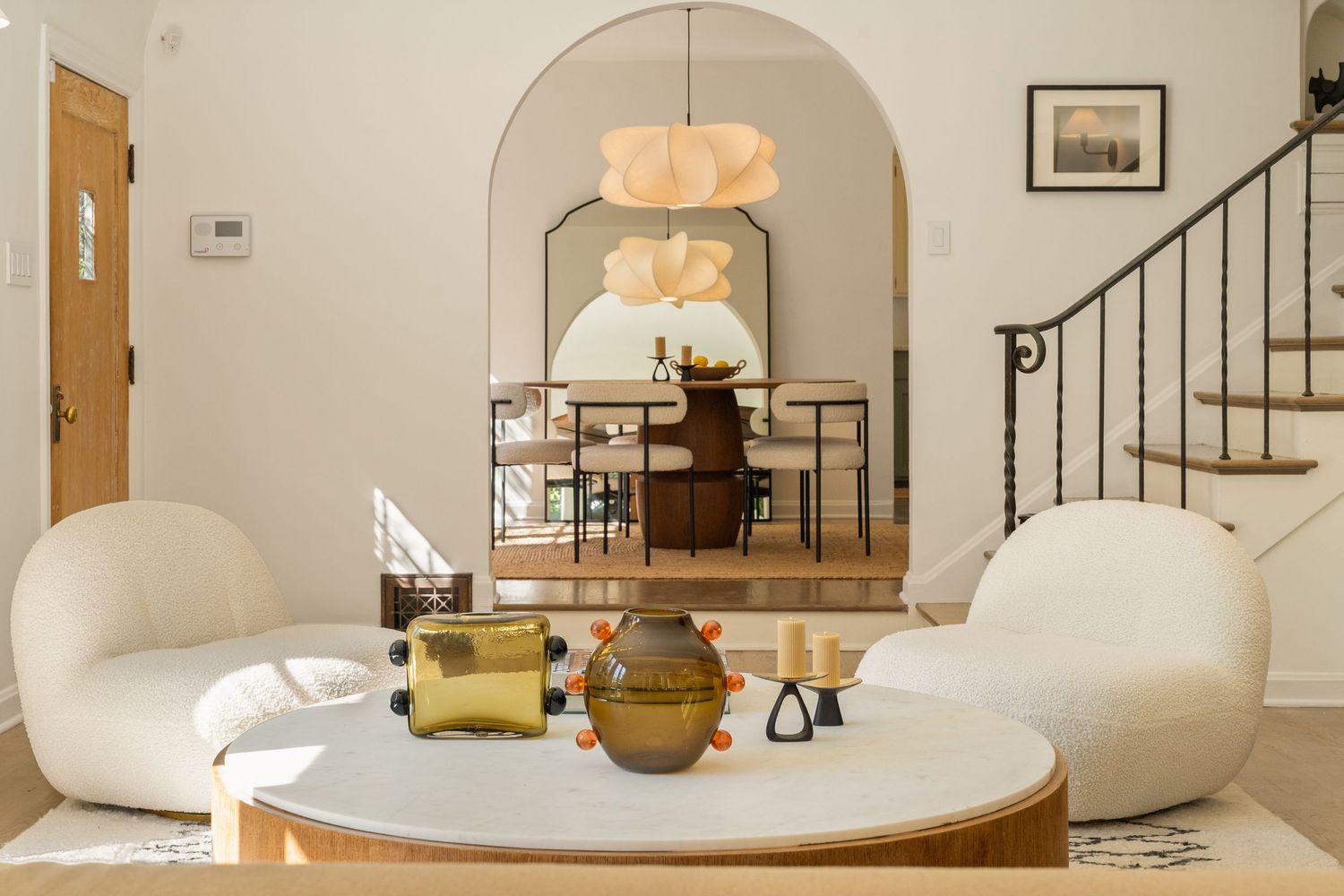 Modern white living room interior with curved sofa, round coffee table and warm lighting fixtures creates cozy atmosphere.