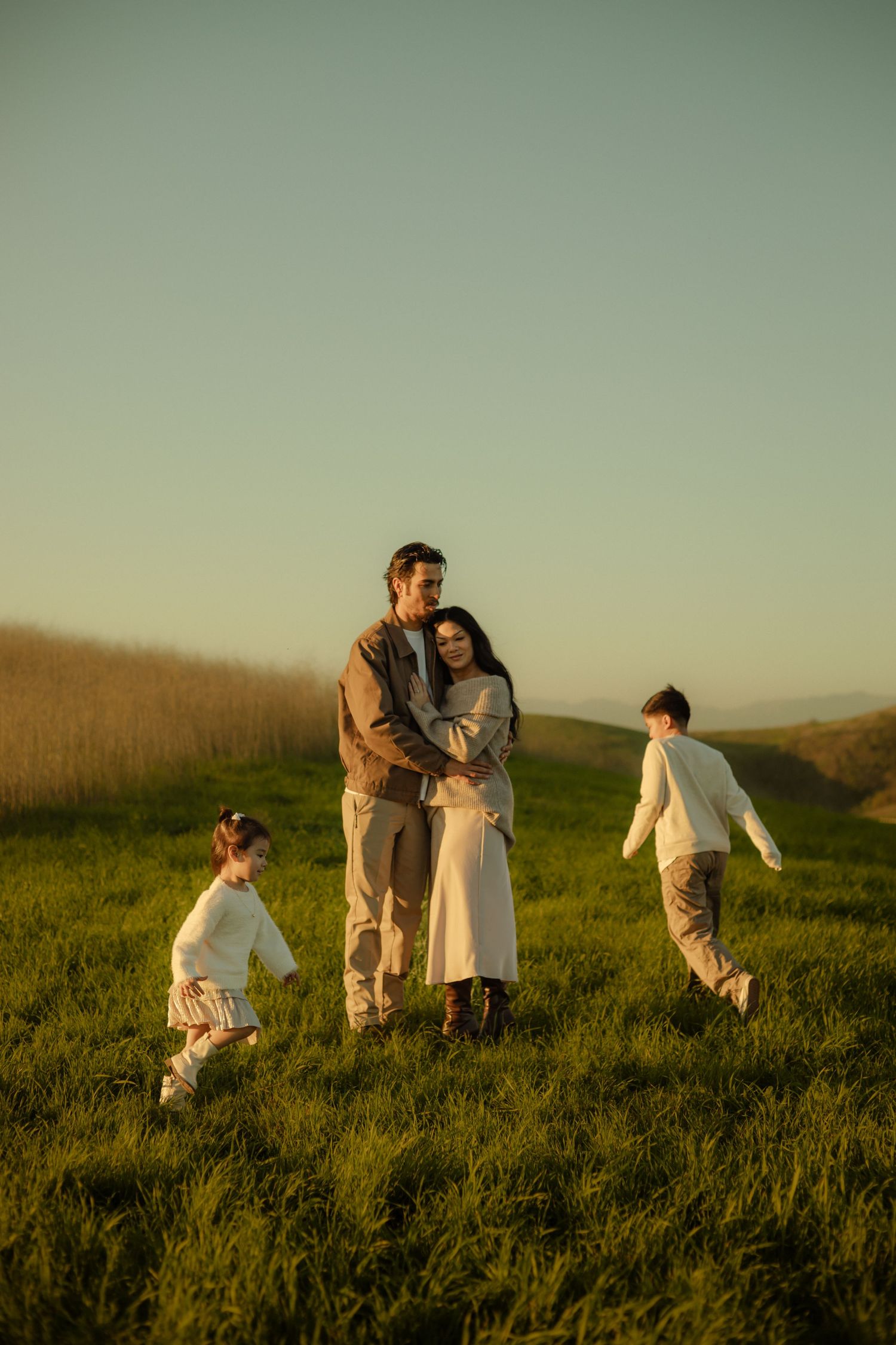 A family enjoys a golden hour sunset in a grassy field in Southern California for their Cinematic Photography Session.