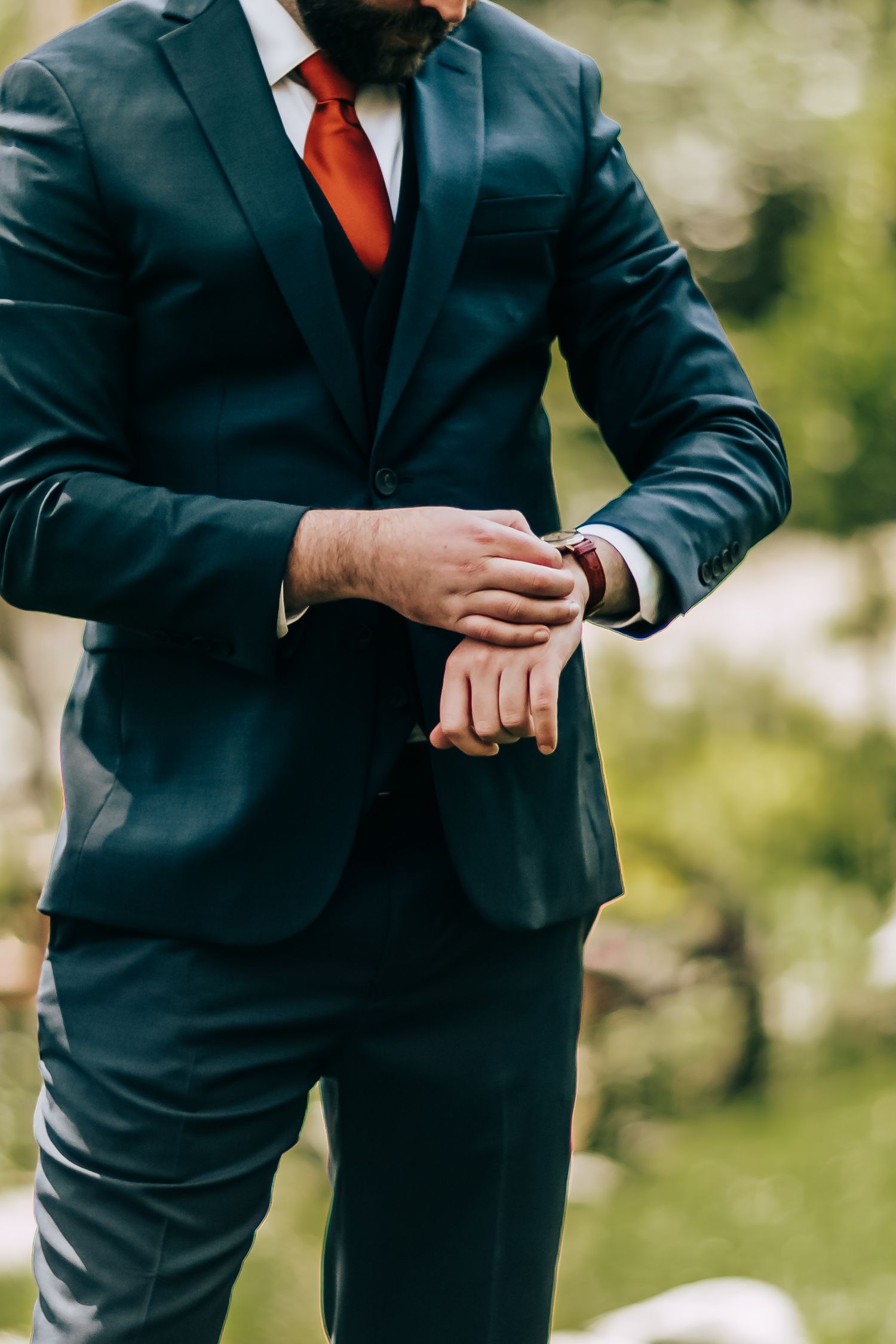 A close-up wedding photo of the groom in his tux and tie checking his wristwatch as he anxiously waits for the wedding ceremony to begin.