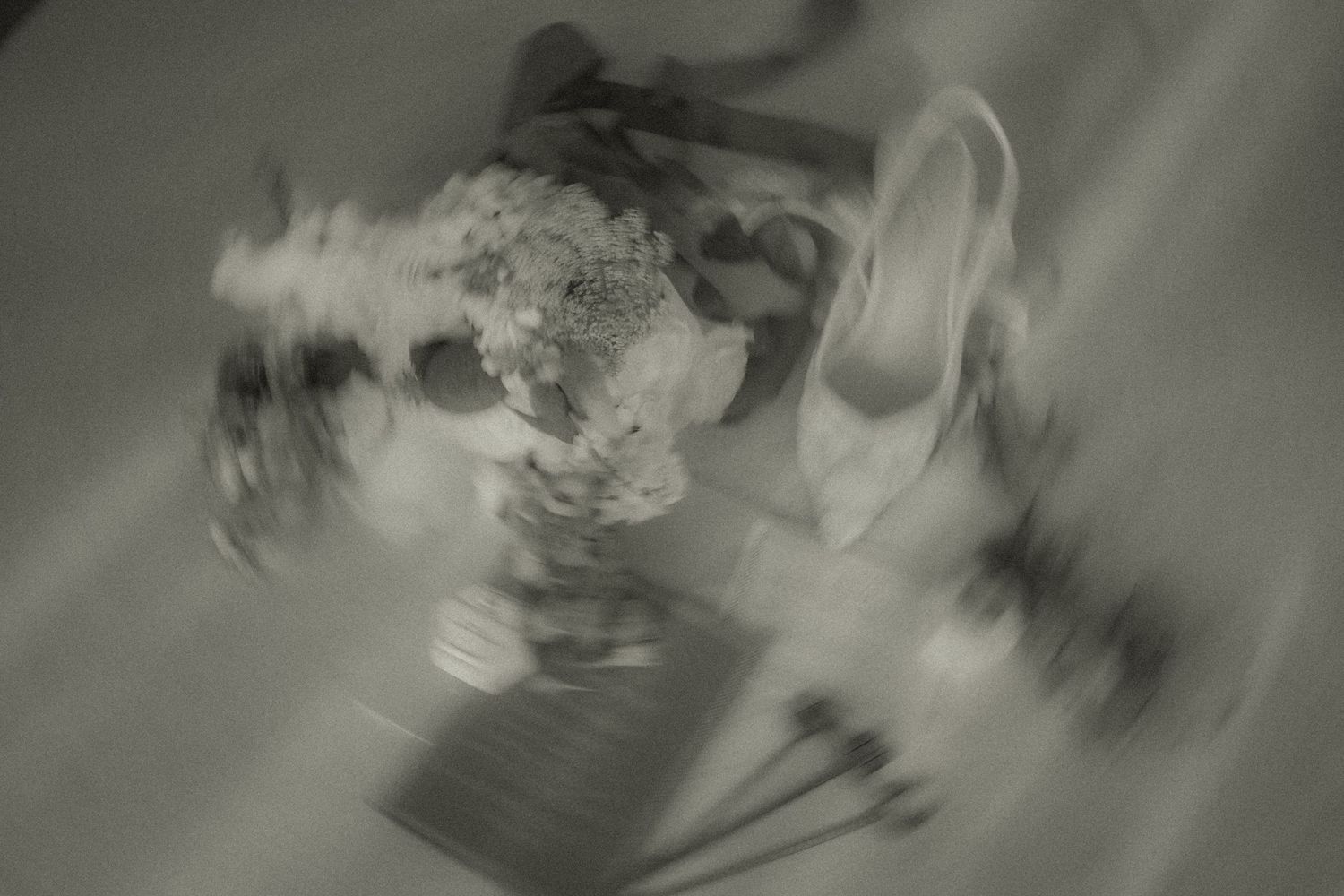 Editorial, artistic, black and white photograph showing swirling blurred motion effects creating an ethereal pattern of wedding photos.