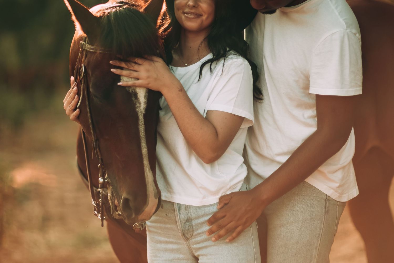 A LA couple in white shirts share tender moments together during a golden hour outdoor photo session with a horse.