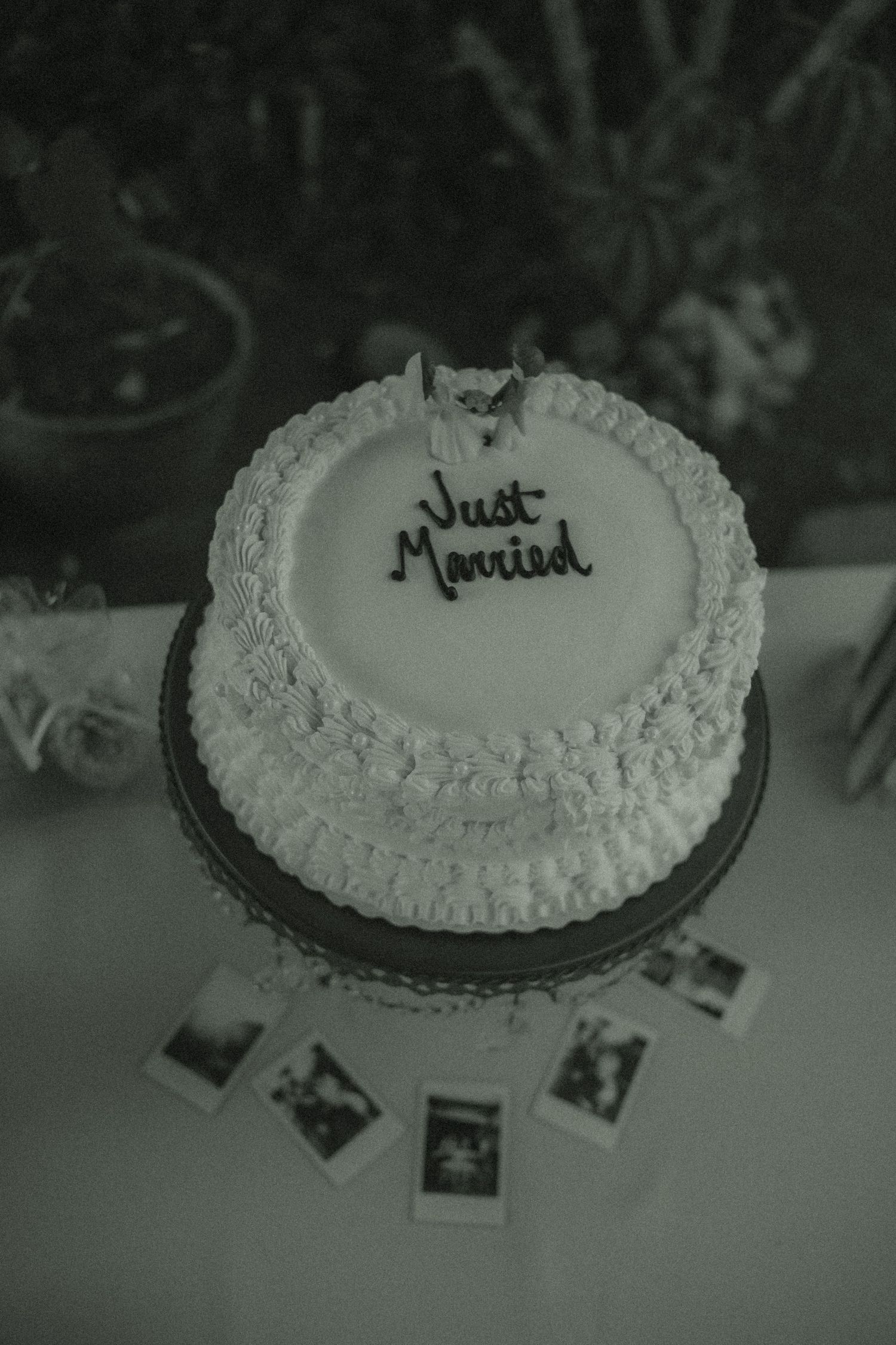 Micro Wedding photography of a small just married cake on display during the wedding reception with polaroids surrounding it on the table.