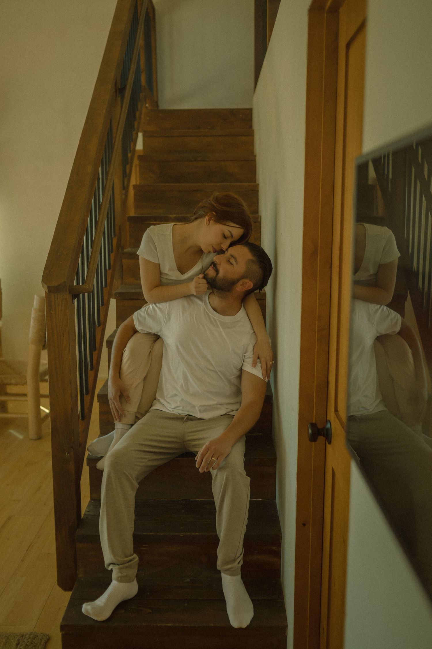 A couple shares an intimate moment together on wooden stairs in a warmly lit Joshua Tree Airbnb