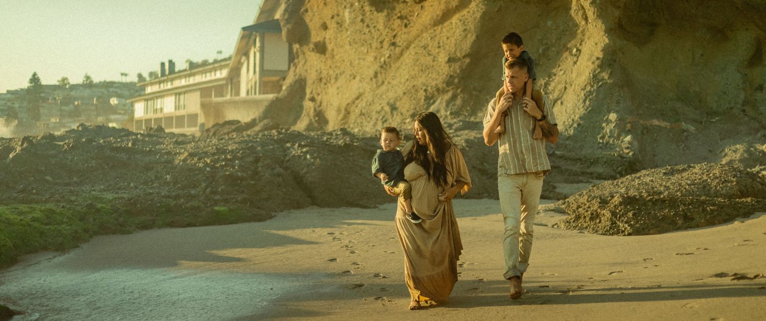 A cinematic photoshoot of a family walking along an oceanside cliff path next to the water in Laguna Beach, California