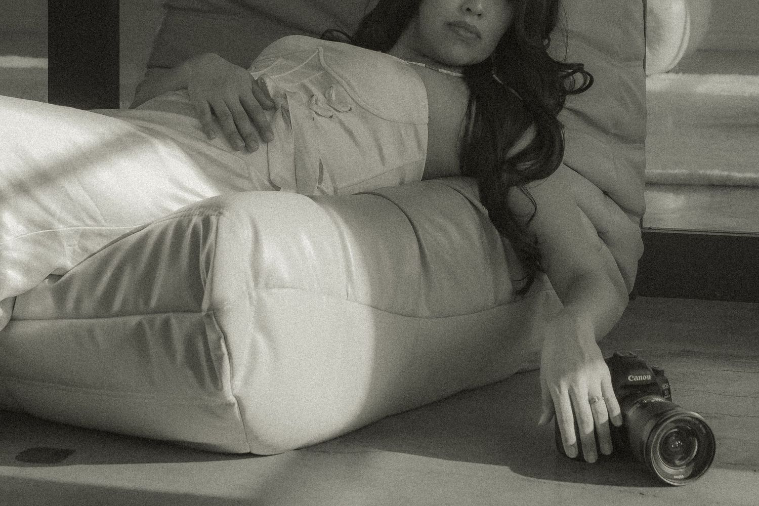 Person lying on floor in black clothing holding a camera while taking creative self-portrait photos.