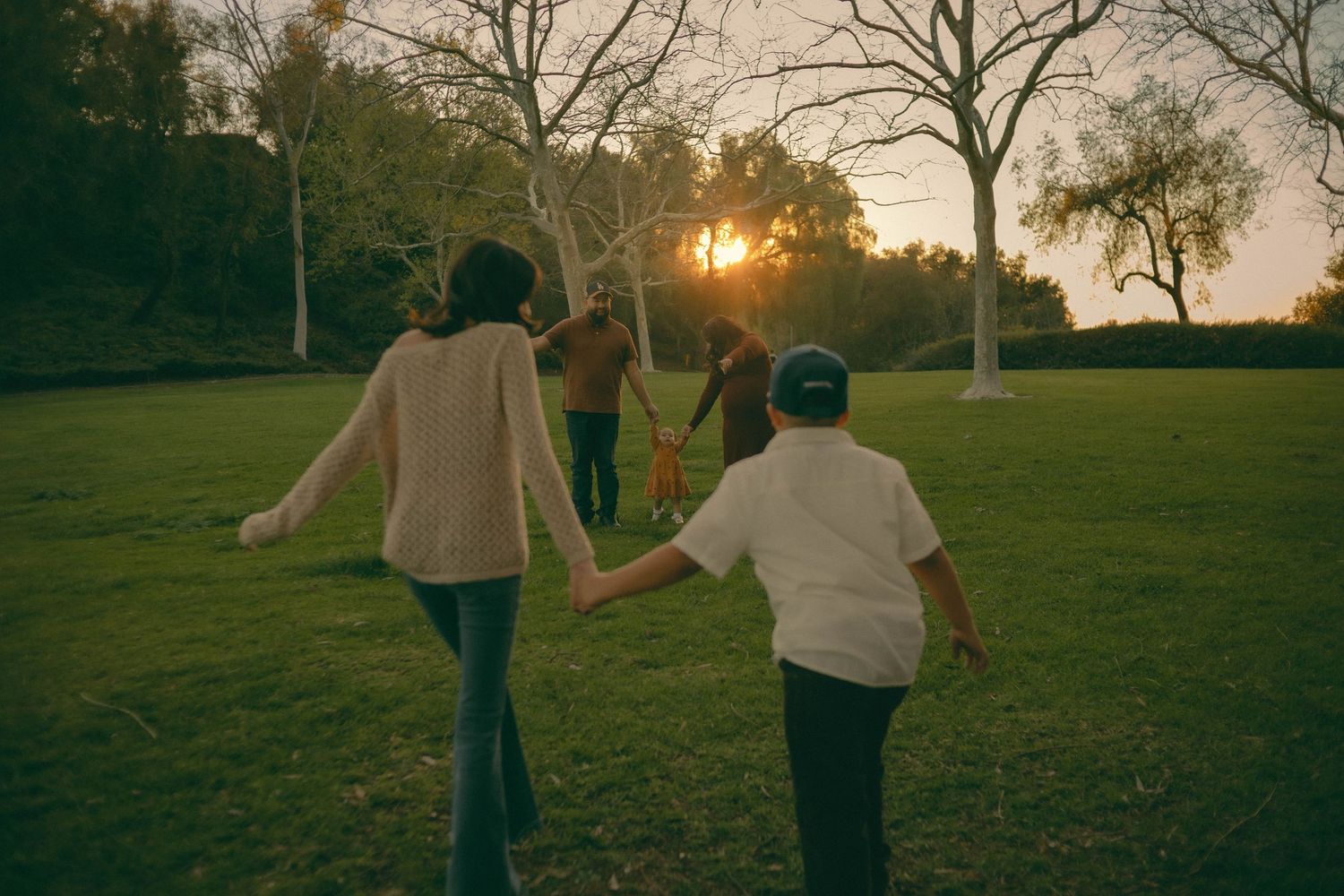 Siblings holding hands while running together during golden sunset hour in Diamond Bar, California for a family photoshoot.