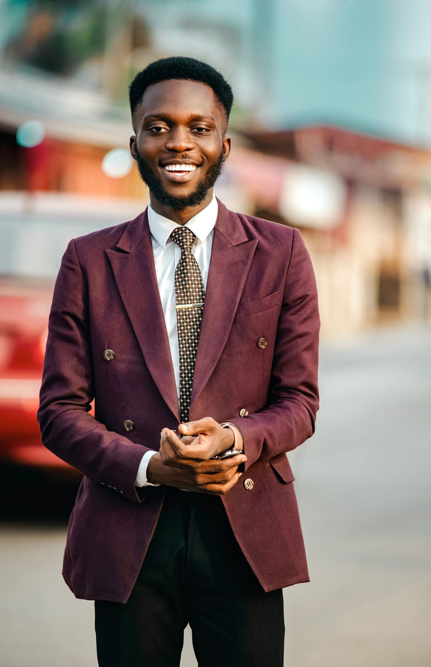 A stylish pose in a burgundy blazer and polka dot tie outdoors.
