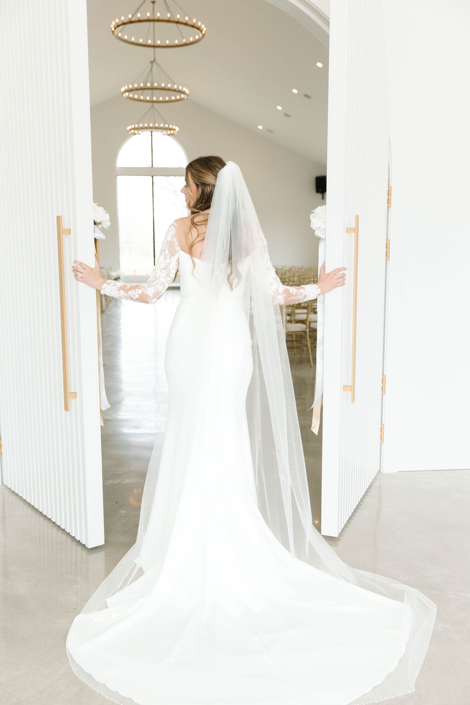 Elegant white wedding dress with flowing train displayed in bright church interior.