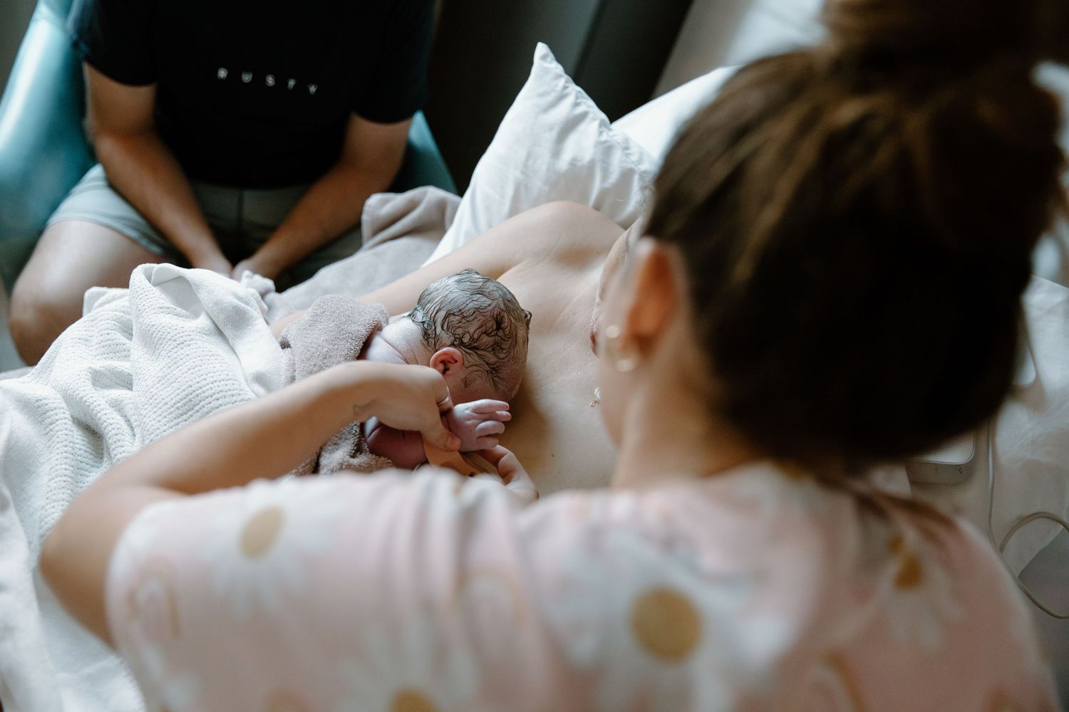 A newborn baby rests in a hospital bed while being cradled in polka dot sleepwear. Birth photoshoot, Karratha, WA