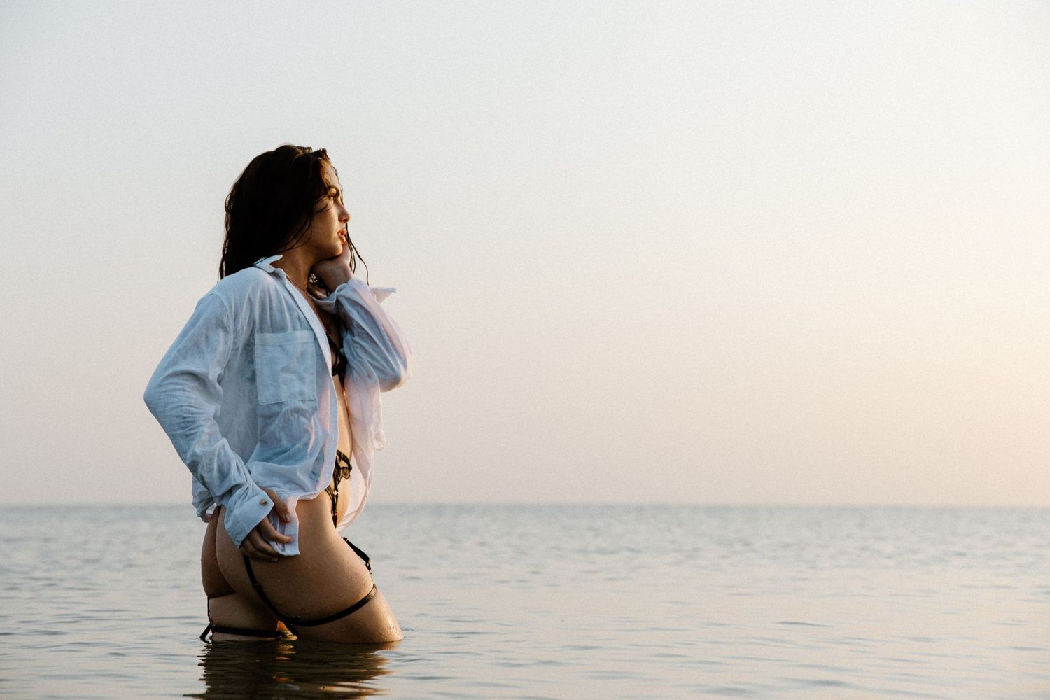 Person standing in shallow ocean water wearing denim jacket during a beach boudoir photography session in Karratha, WA