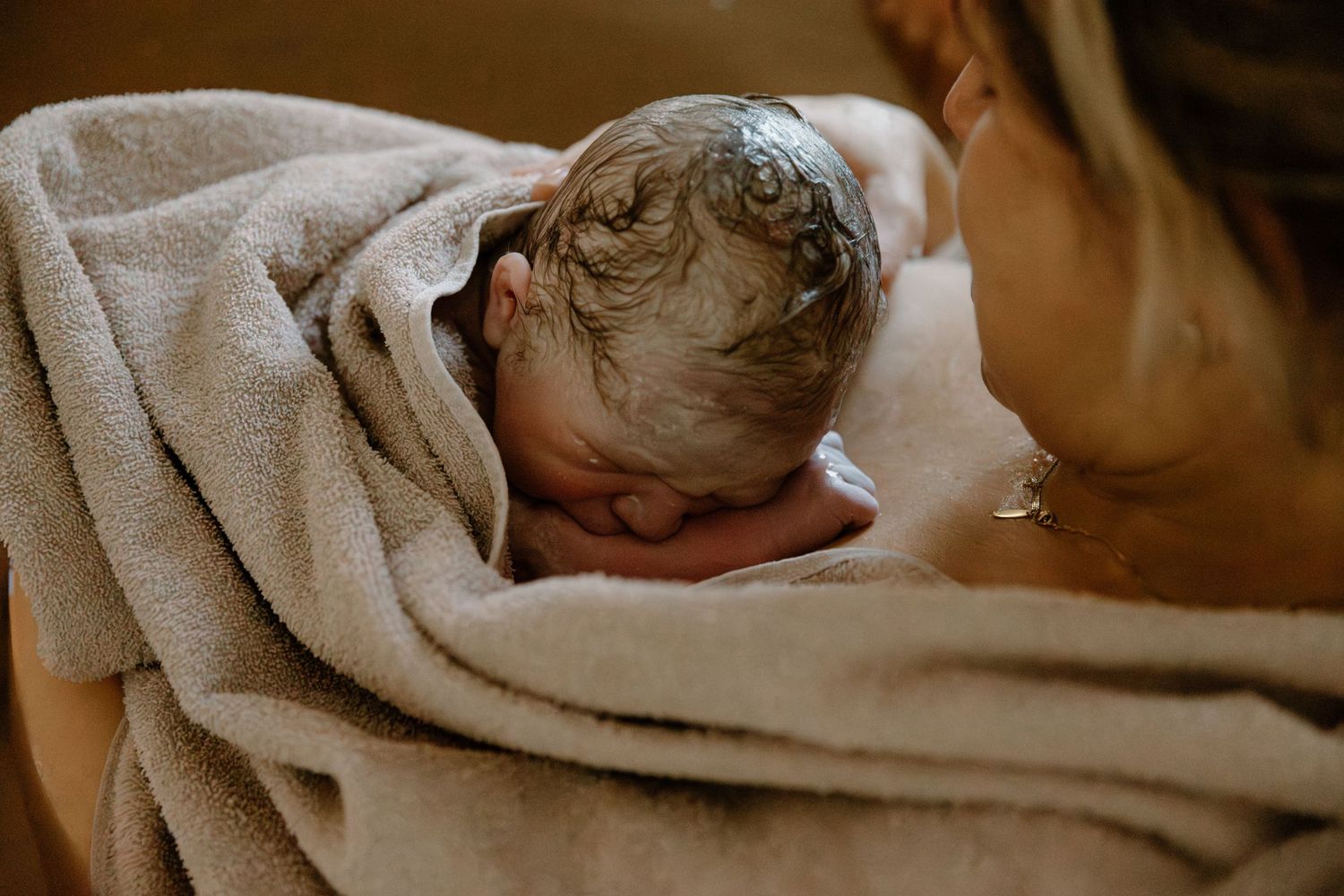 Newborn baby wrapped in soft beige towel after birth, during a birth photography session, located in Karratha, WA