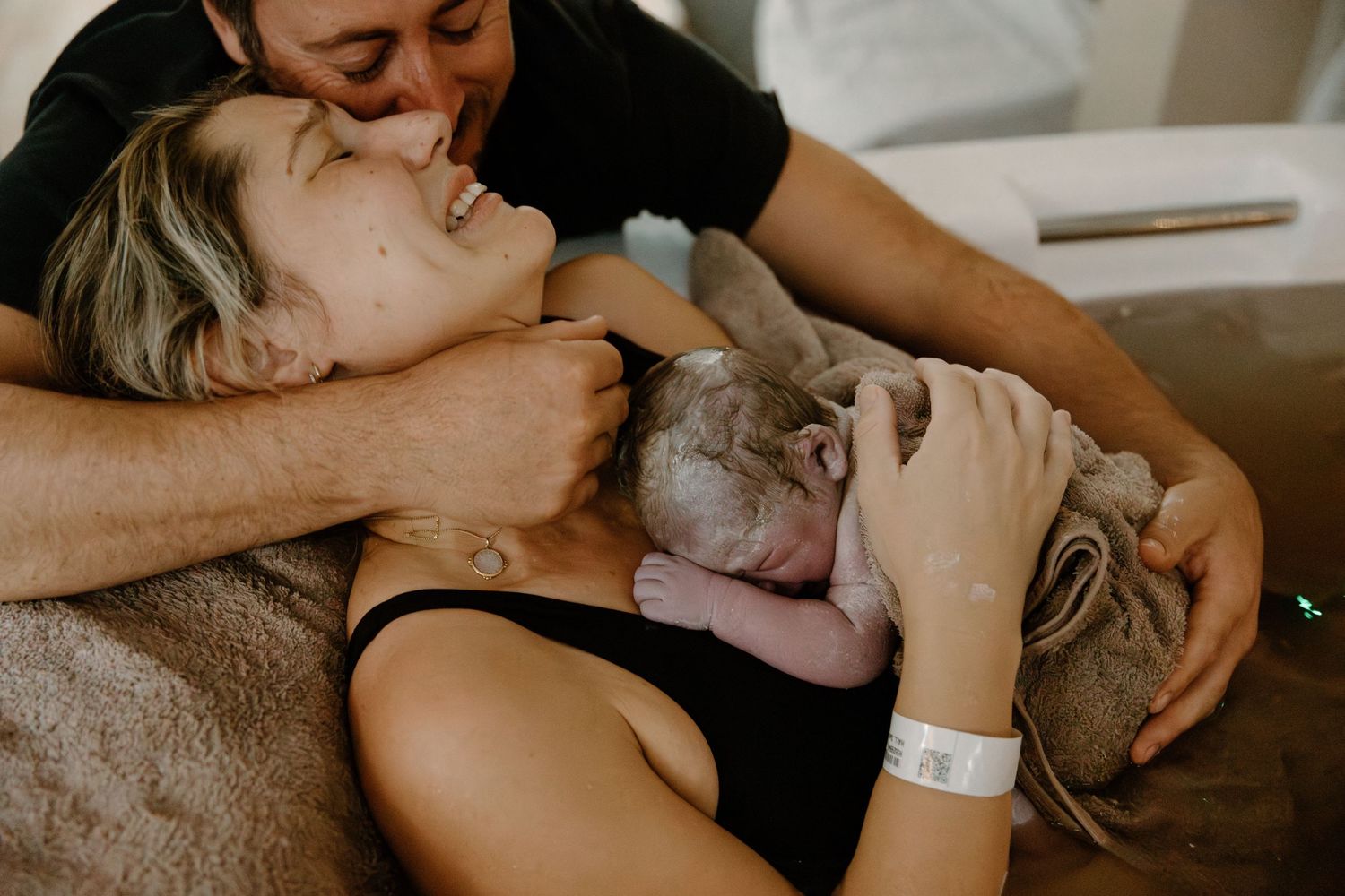 Emotional birth scene showing tender moment of first skin-to-skin contact with newborn during a birth photoshoot in Karratha, WA