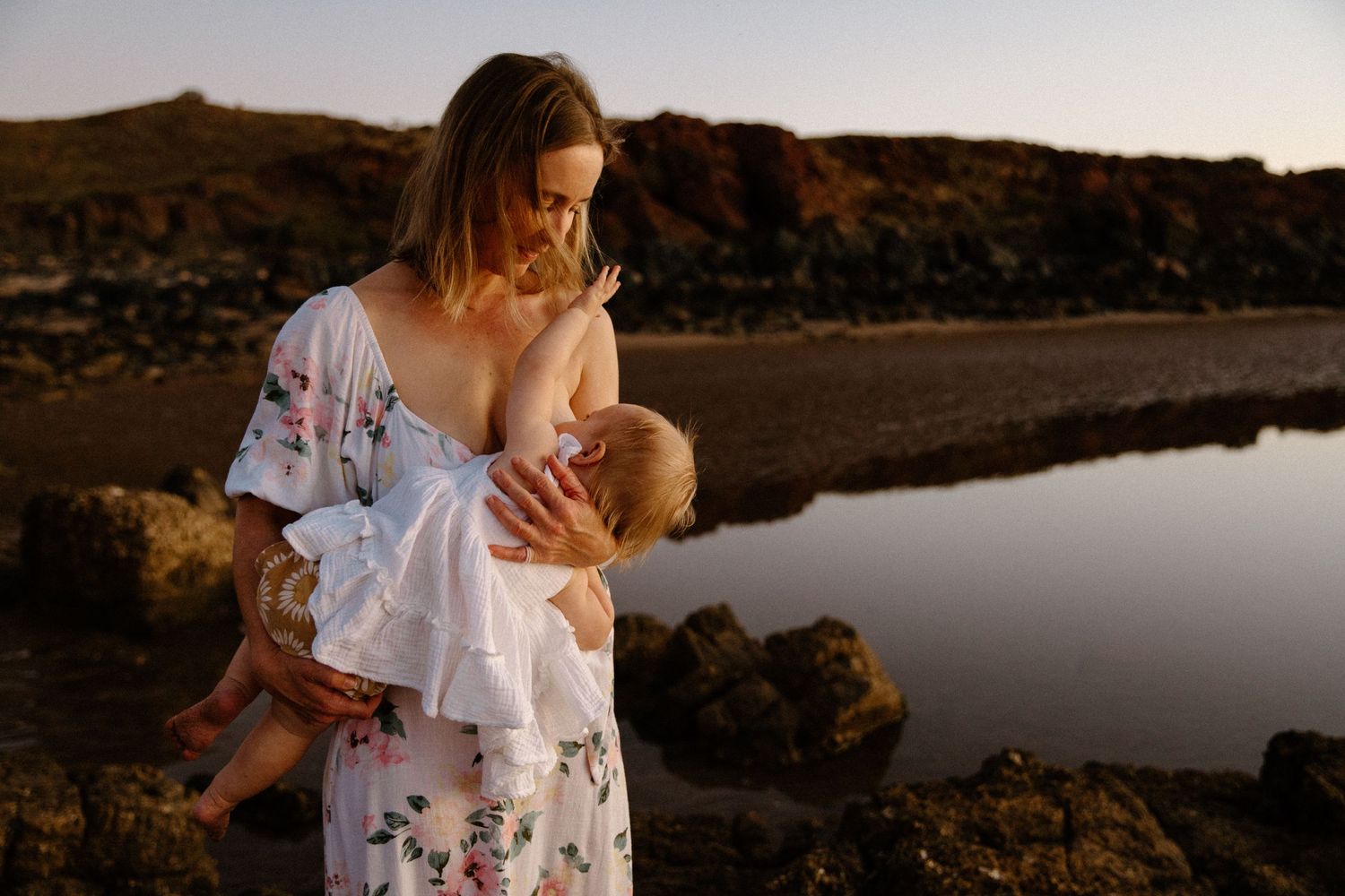 A sunset motherhood photography session, as the mother breastfeeds her baby, in Wickham, WA