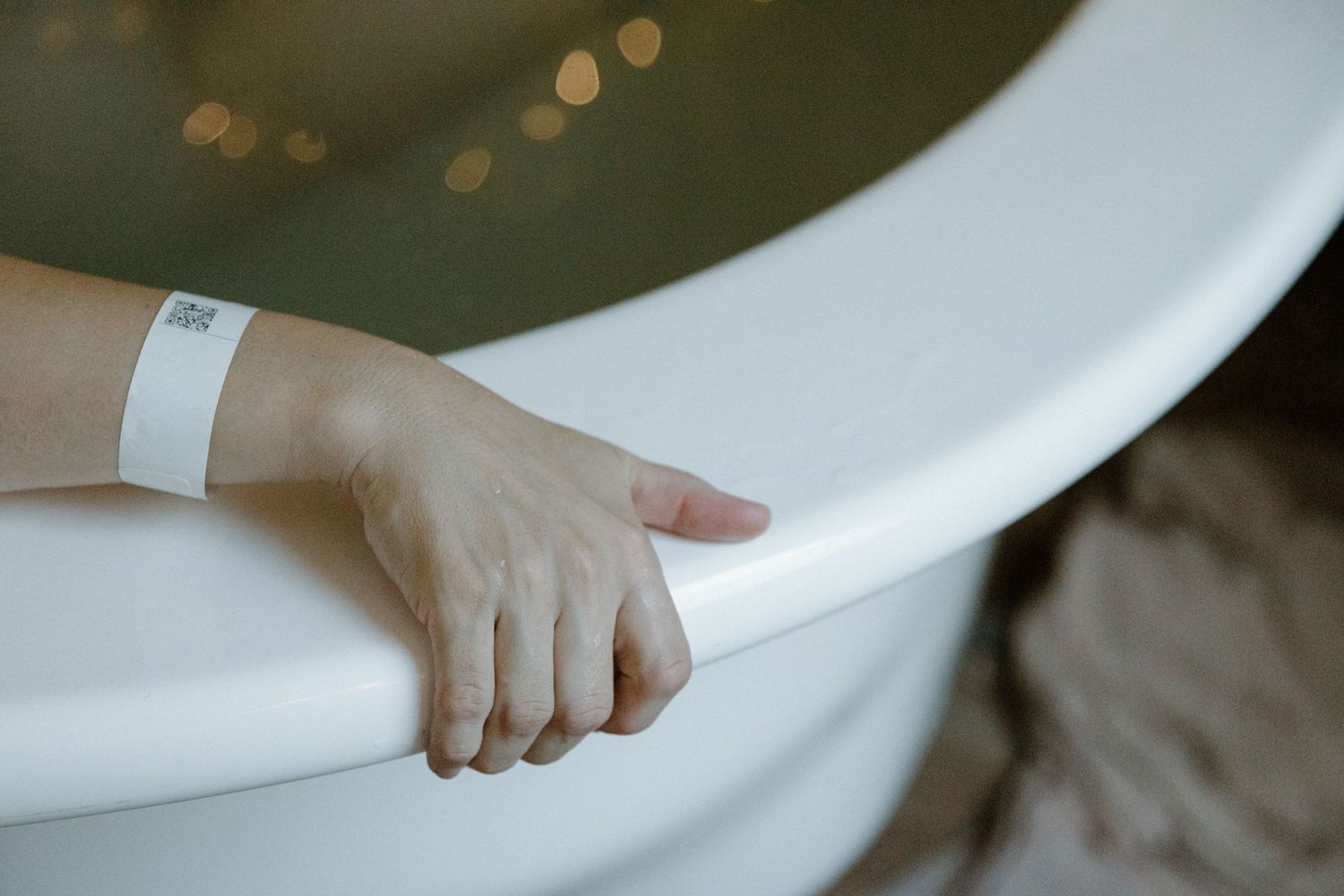 Mum's hand grips the edge of the water bath while experiencing a contraction during a birth photoshoot in Karratha, WA