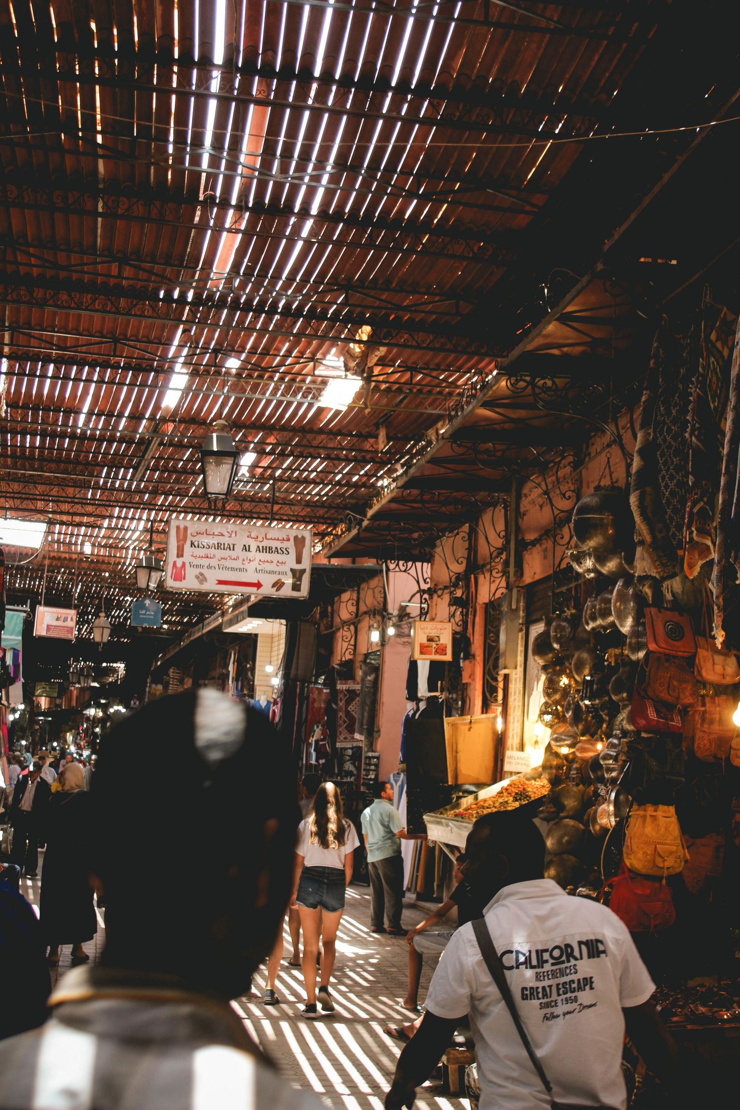 Market in the Medina of Marrakech, Morocco, sunlight seeping through wooden slats; bustling marketplace, Moroccan travel, lanterns, lights.