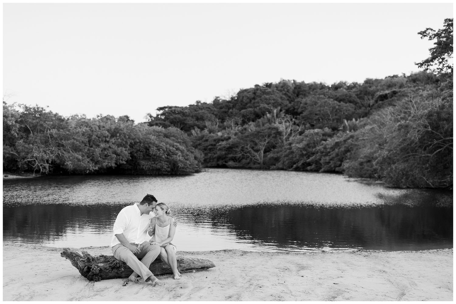 Punta Mita family photographer, engagement session by a tranquil lake surrounded by trees and natural vegetation.