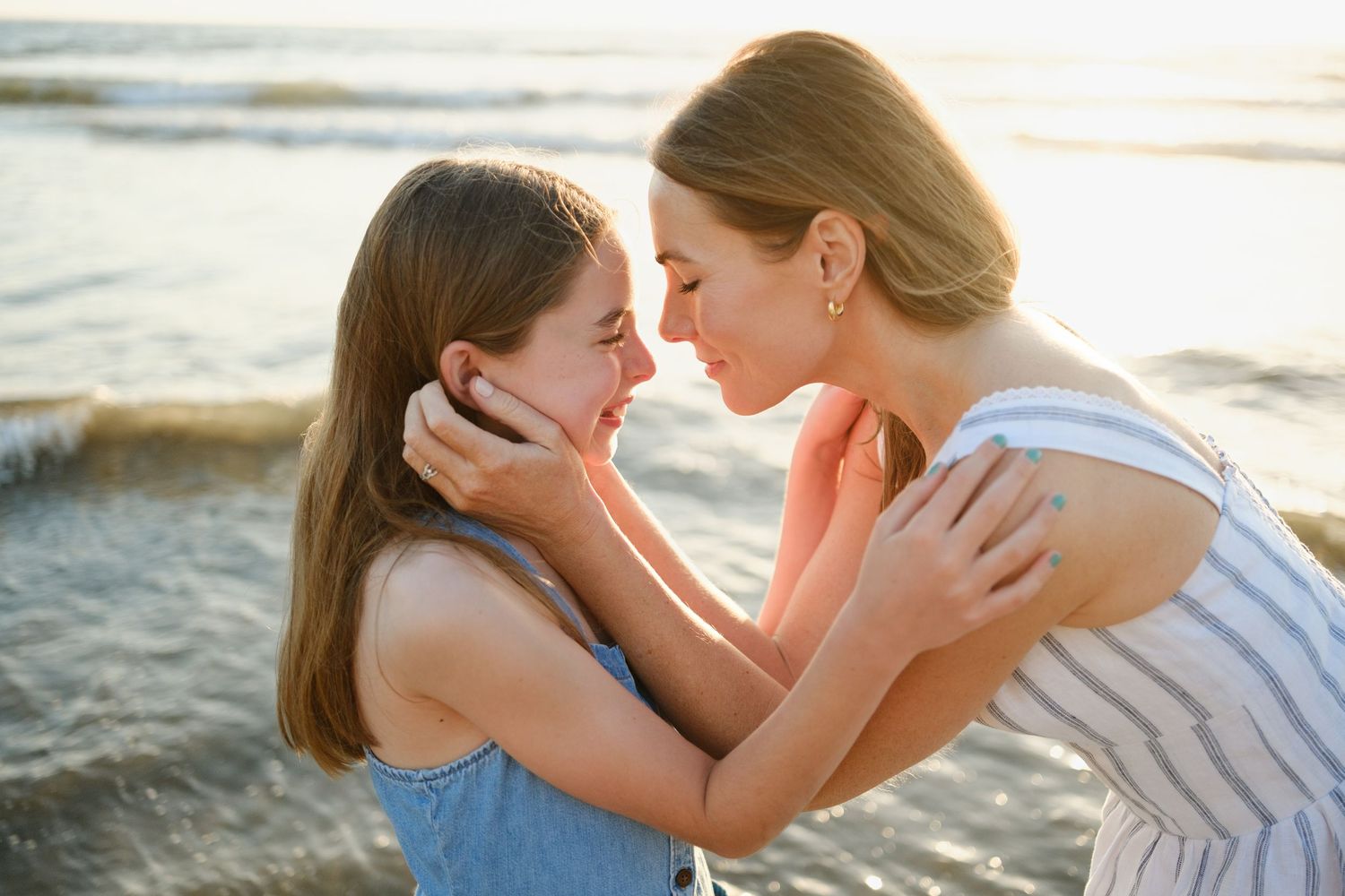 Two people share an intimate moment together on a sunny beach at sunset.