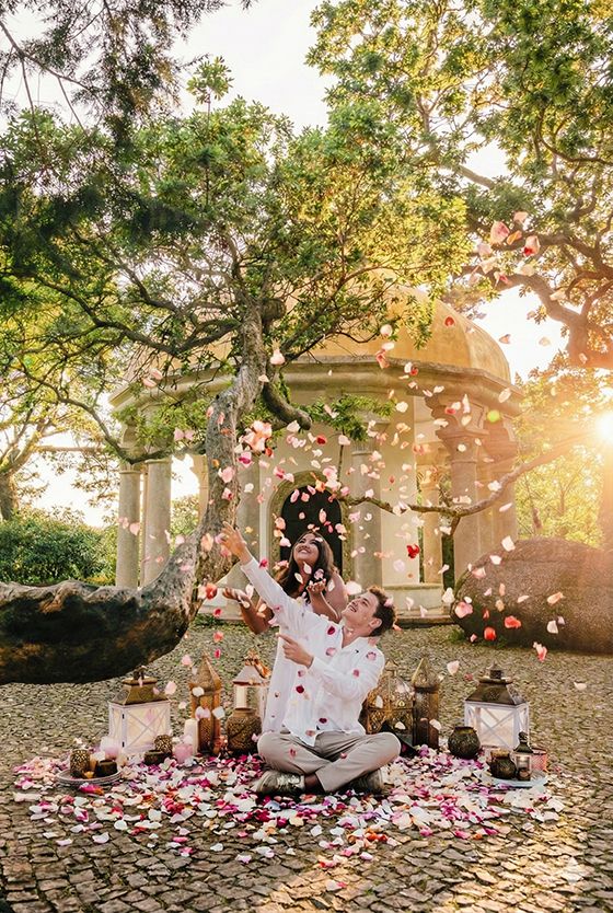 Rose petals fall in slow motion around a romantic stone gazebo at sunset creating a magical wedding moment.