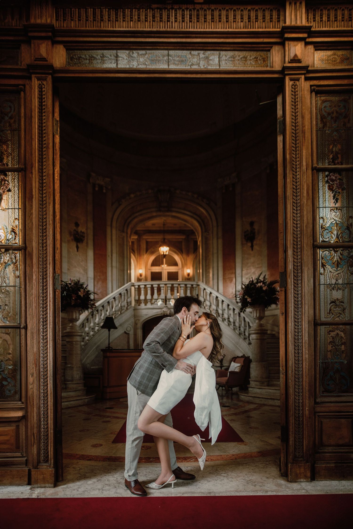 Romantic couple shares intimate dance moves in an ornate vintage ballroom with elegant wood paneling and lighting.
