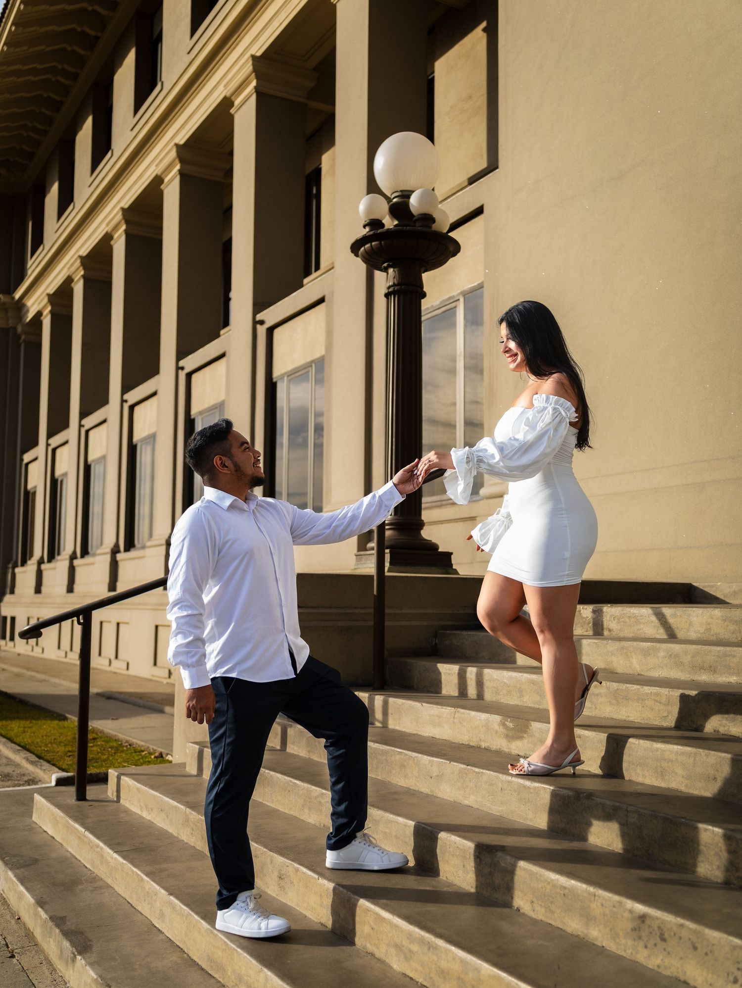 A person in a white shirt and dark pants demonstrates a sequence of dance movements on concrete steps.