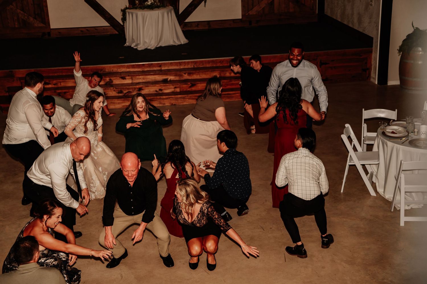 Wedding reception guests dancing and celebrating on the dance floor at a rustic barn venue.