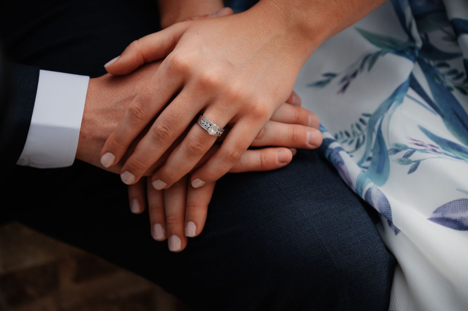 Close-up of couple's hands stacked together, woman wearing a diamond wedding ring, symbolizing love and commitment.