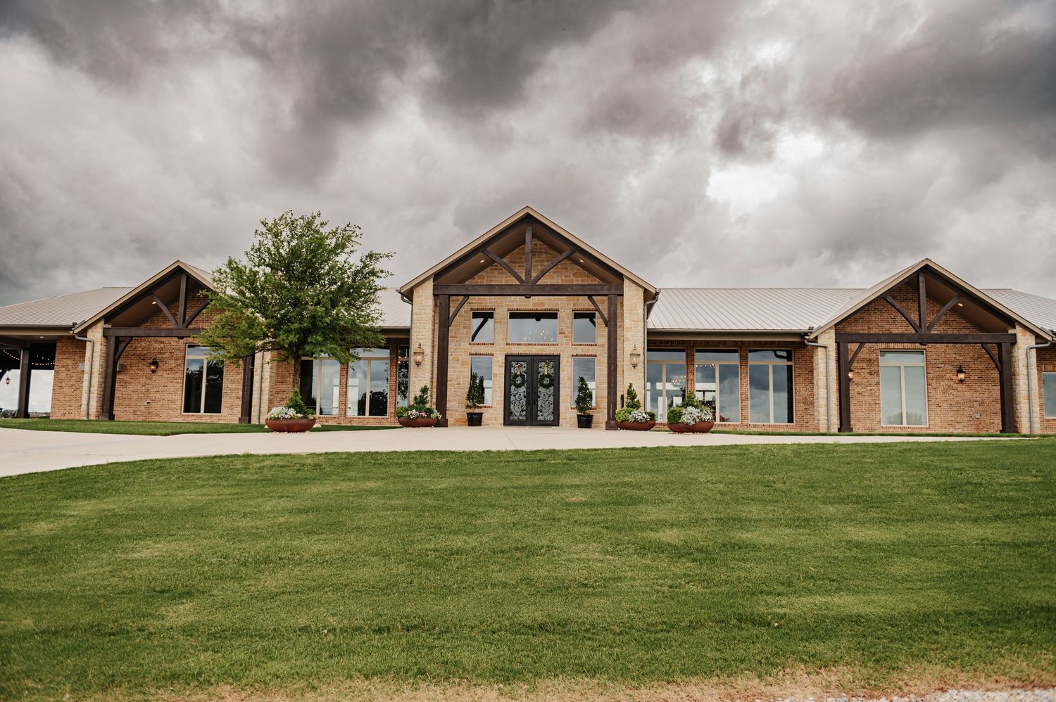 Elegant rustic wedding venue with wooden architecture and manicured lawn under cloudy skies.