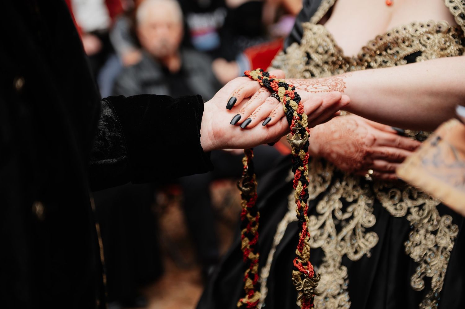 Close-up of hands exchanging colorful beaded garland during a traditional wedding ceremony.