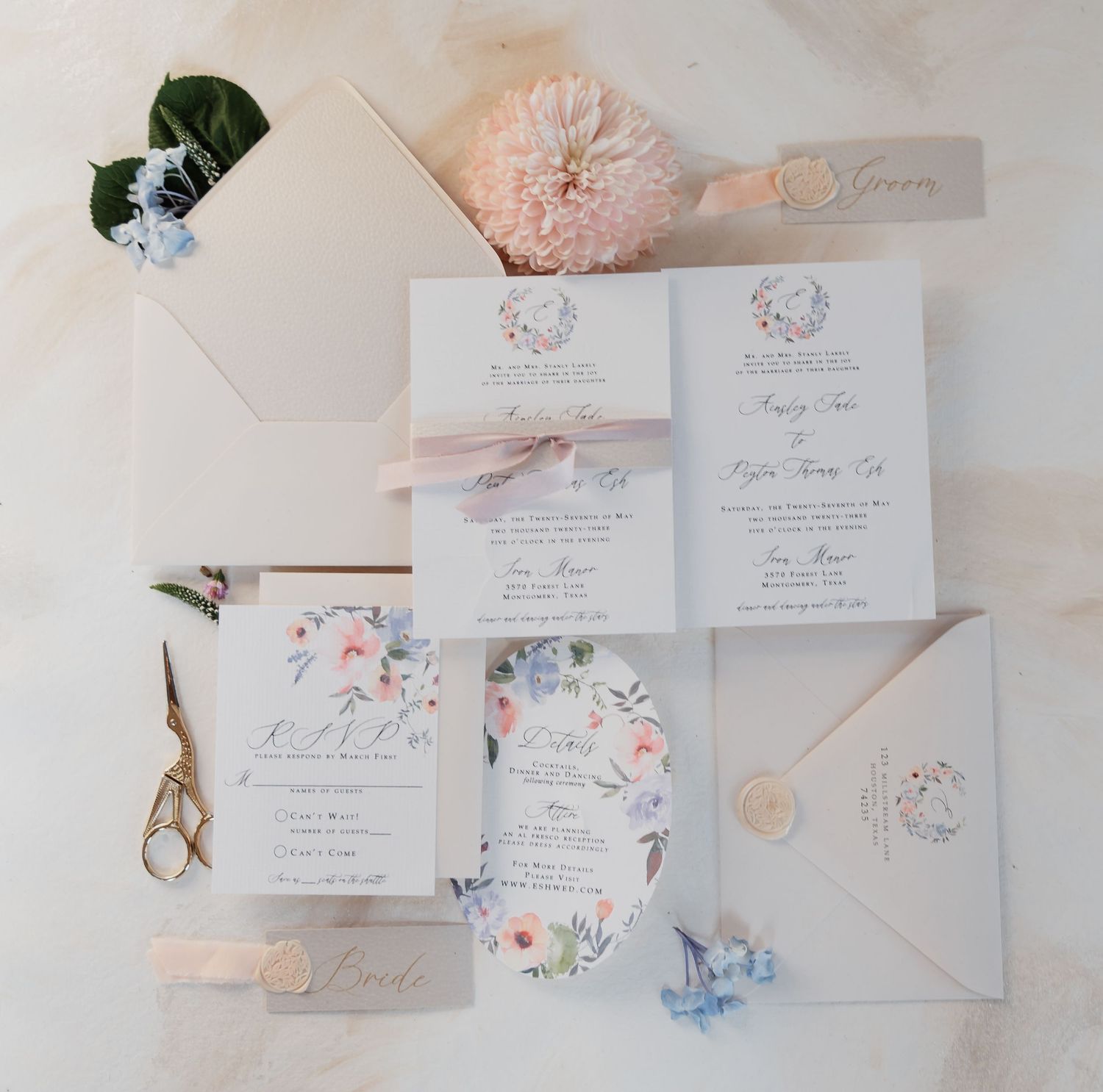 Elegant wedding invitation suite with floral details, blush envelopes, wax seal, and pink blooms on white background.