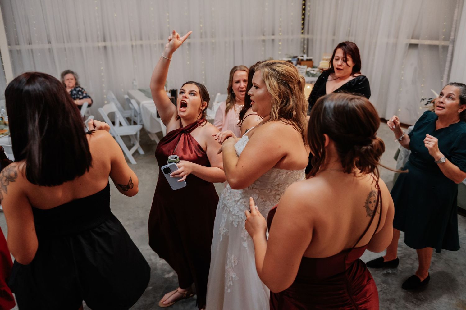 Bride and bridesmaids dancing and celebrating joyfully at a wedding reception party.